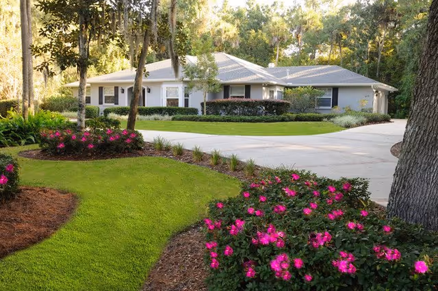 Timberlane Lodge assisted living facility shown with manicured lawn and flower beds.