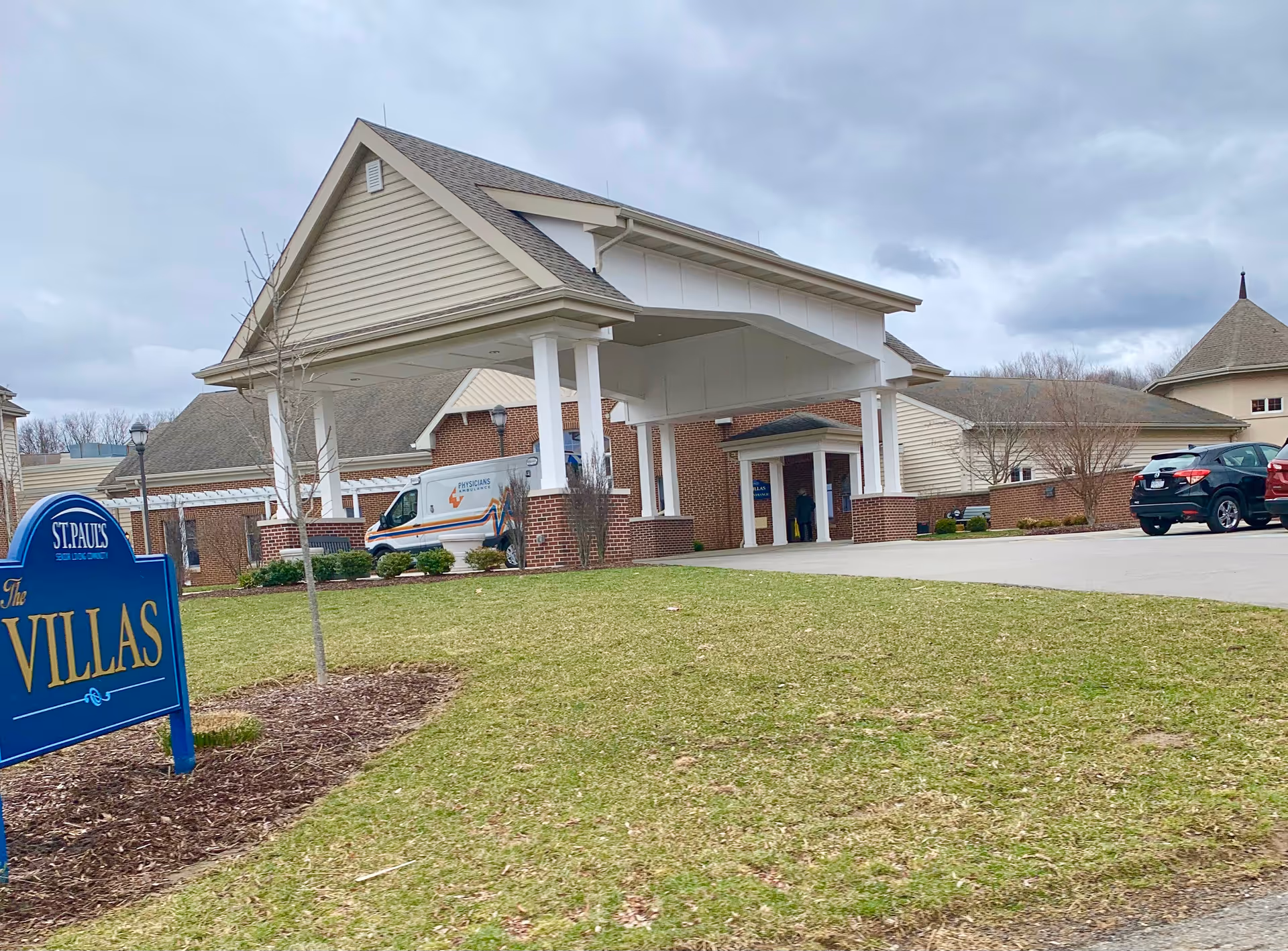Exterior view of St. Pauls Villas entrance with porte-cochere and parked vehicles