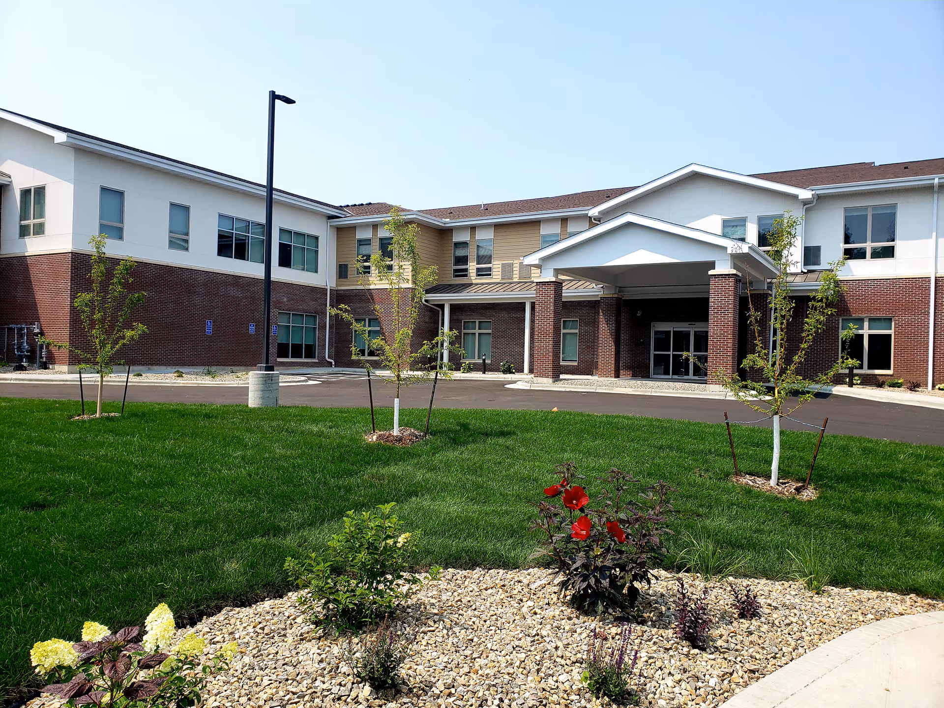 Exterior view of Cascade Creek senior living facility with lawn, shrubs, and entrance canopy.