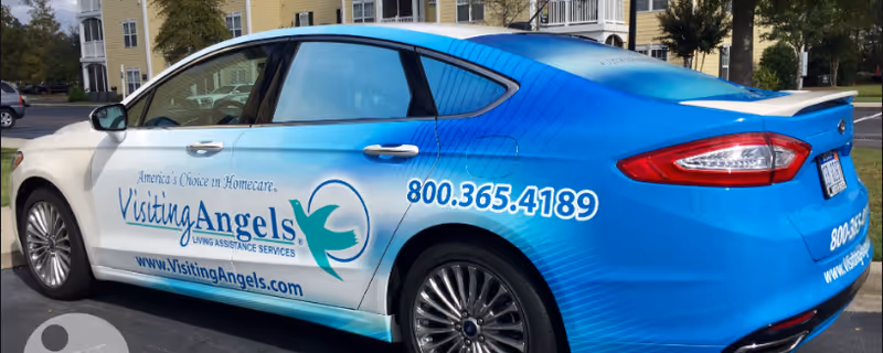 Blue Visiting Angels car with logo and contact number parked outdoors in Charleston.