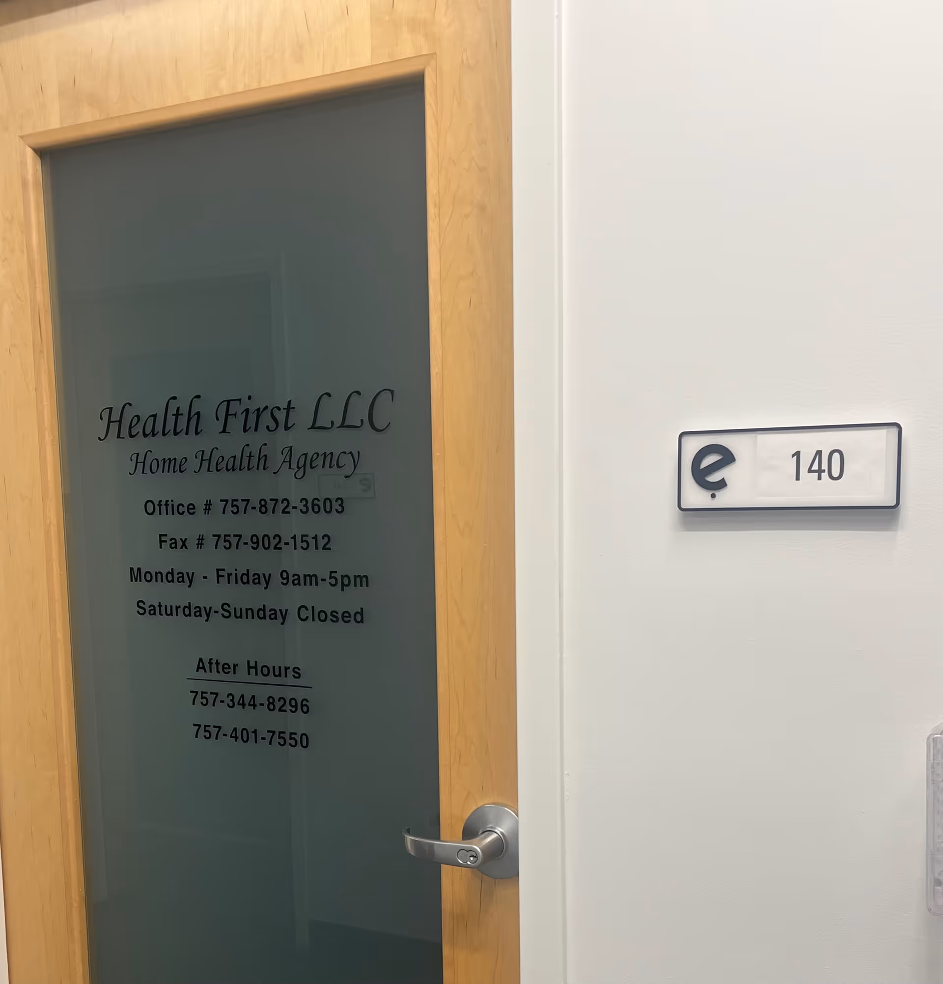 Wood-framed glass door with Health First LLC office sign and room number plaque.