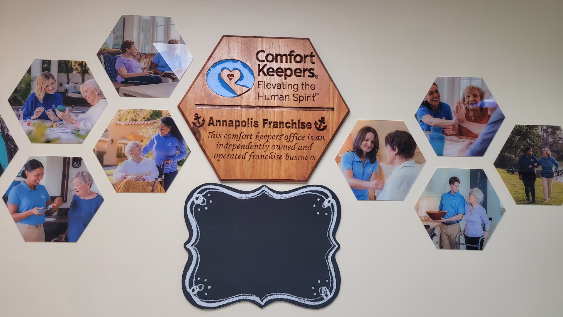 Interior wall features a hexagonal photo collage surrounding a wooden Comfort Keepers sign.