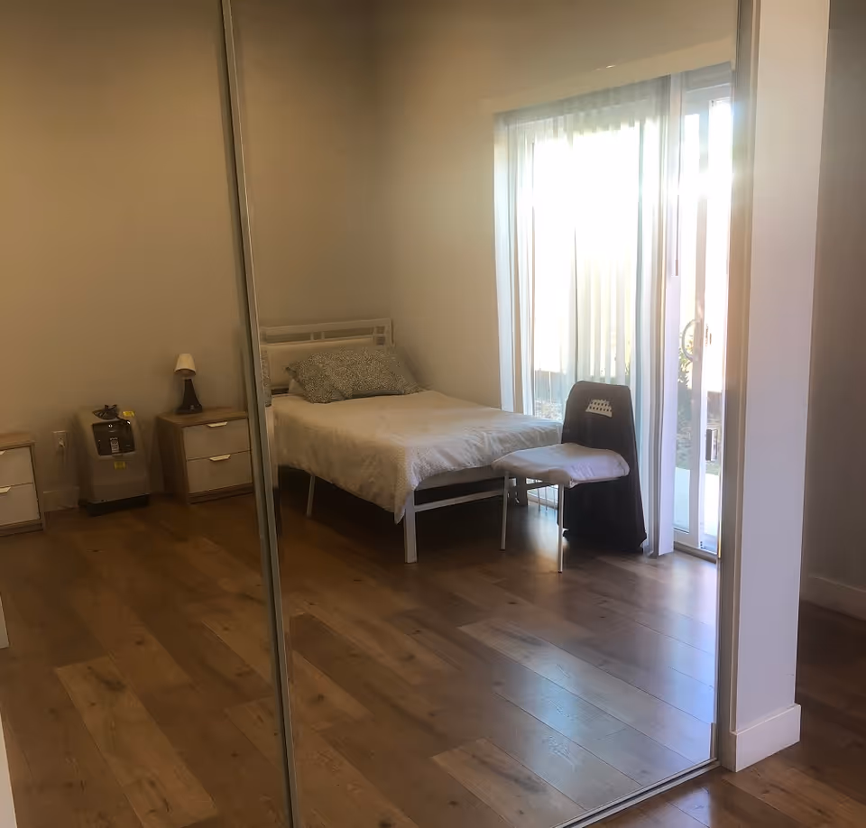 Bright senior living bedroom with bed, nightstands, and a glass door to outdoors.