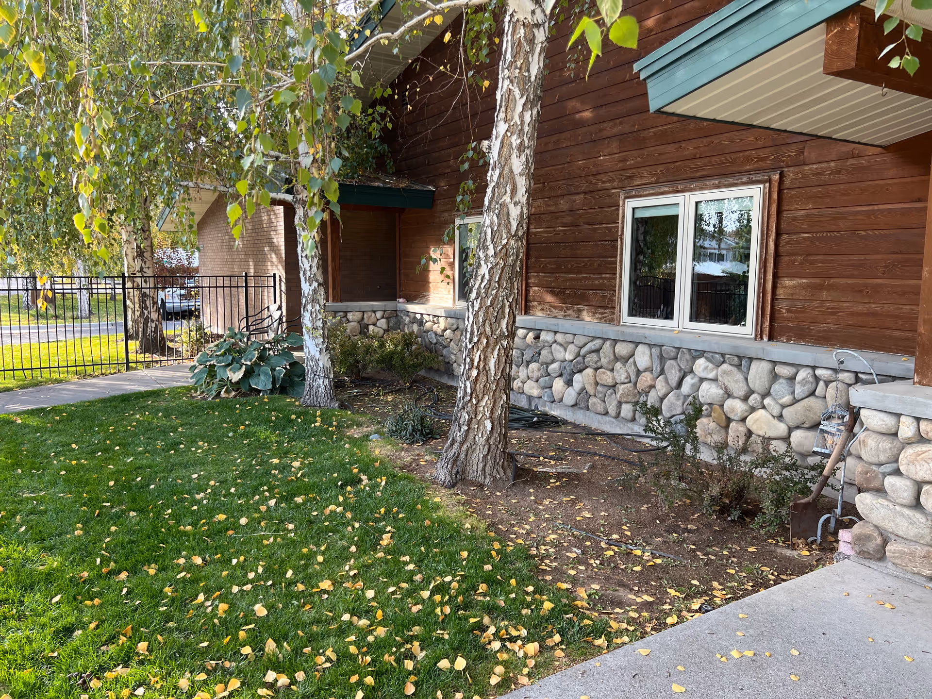 Exterior view of Creekside Residential Care Center with stone foundation, trees, and lawn.