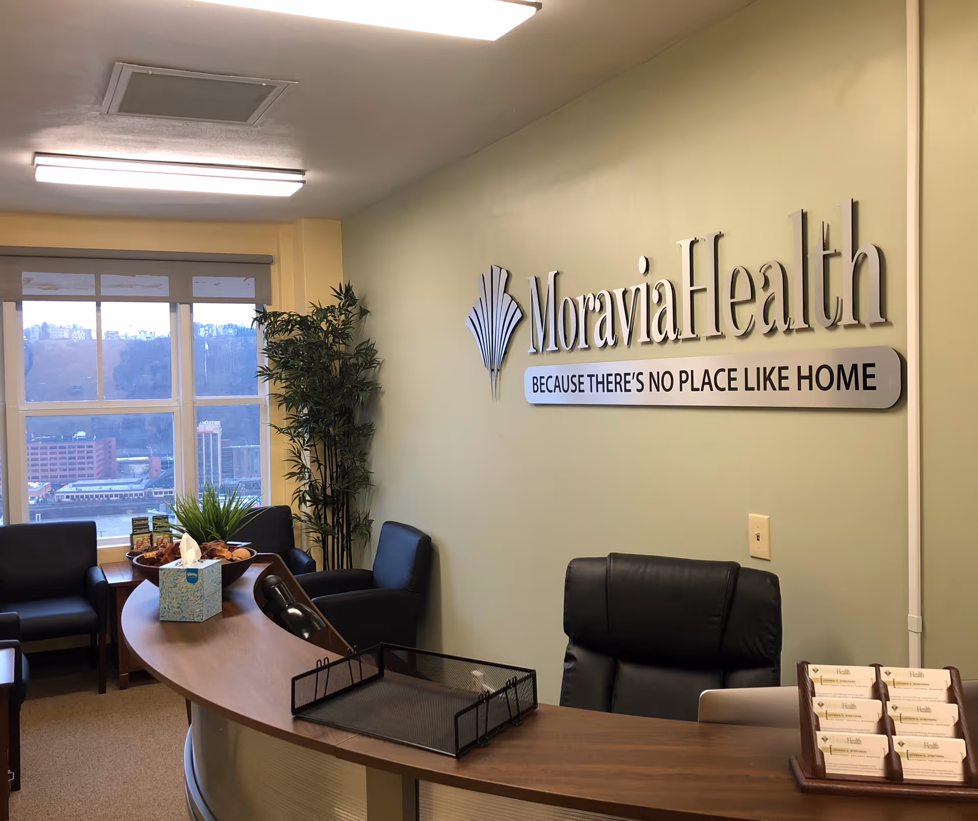 Reception desk in Moravia Health Pittsburgh lobby with seating and plants.