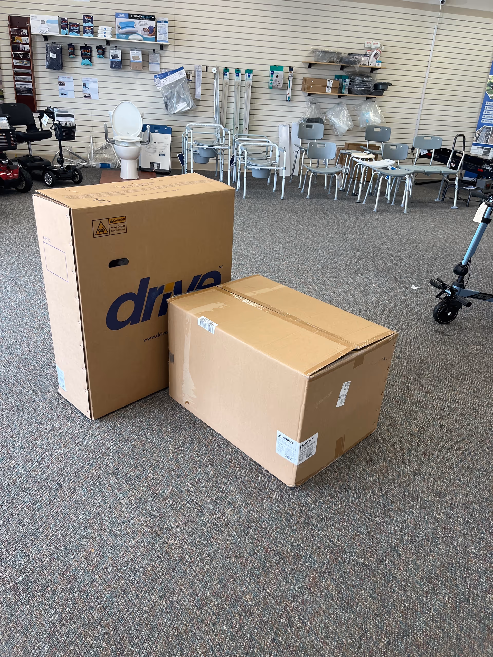 Two large cardboard boxes sit on a carpeted showroom floor in a senior care facility.