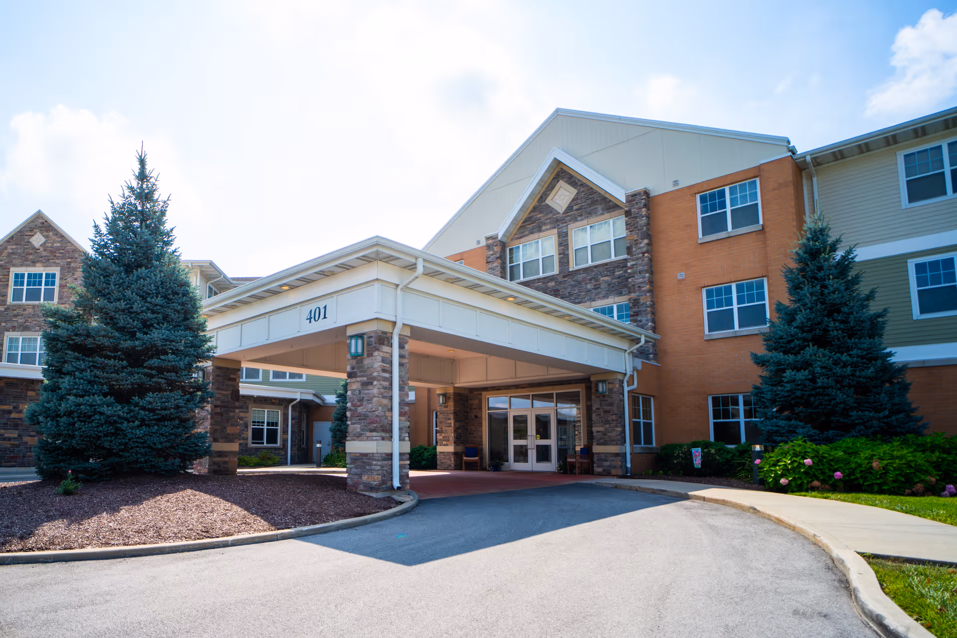 Front exterior of a senior living facility with a covered entrance and stone columns.