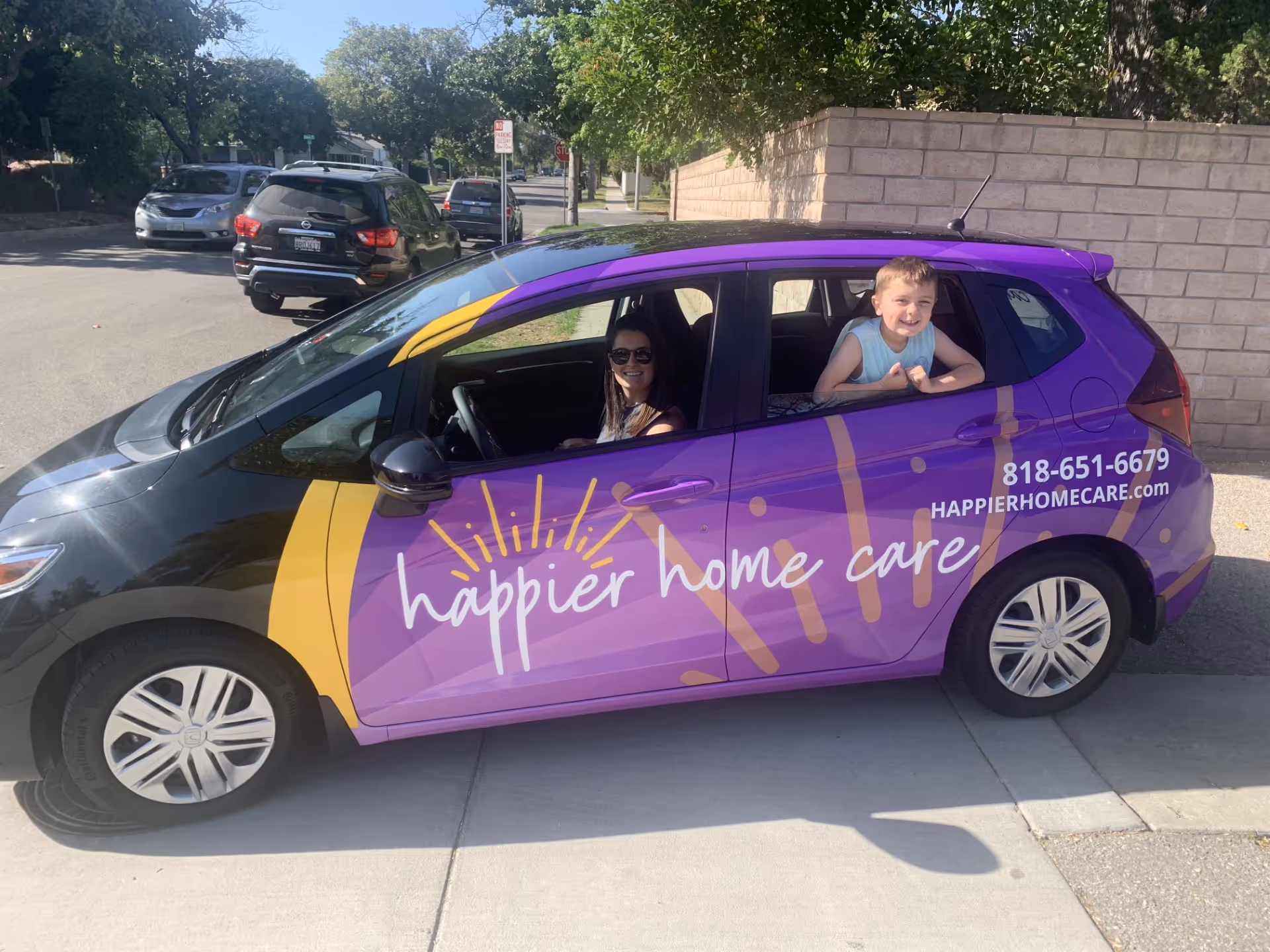 Purple Happier Home Care car with two people inside parked on the street