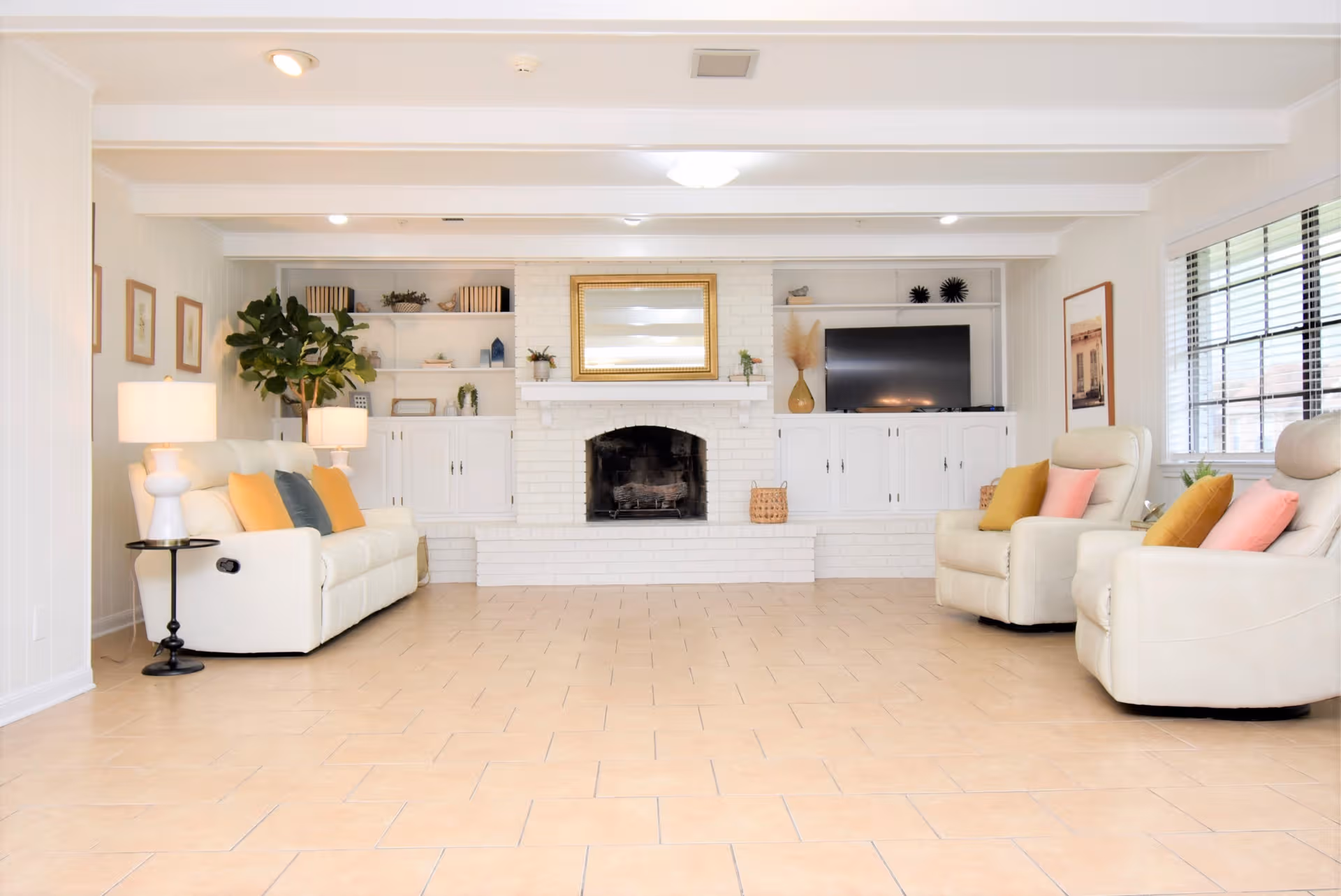 Bright living room with white sofas, built-in cabinets, and a central fireplace.