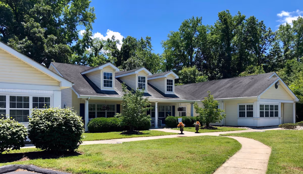 Sunlit, single-story retirement home with beige siding, dormer windows, and curved walkway.