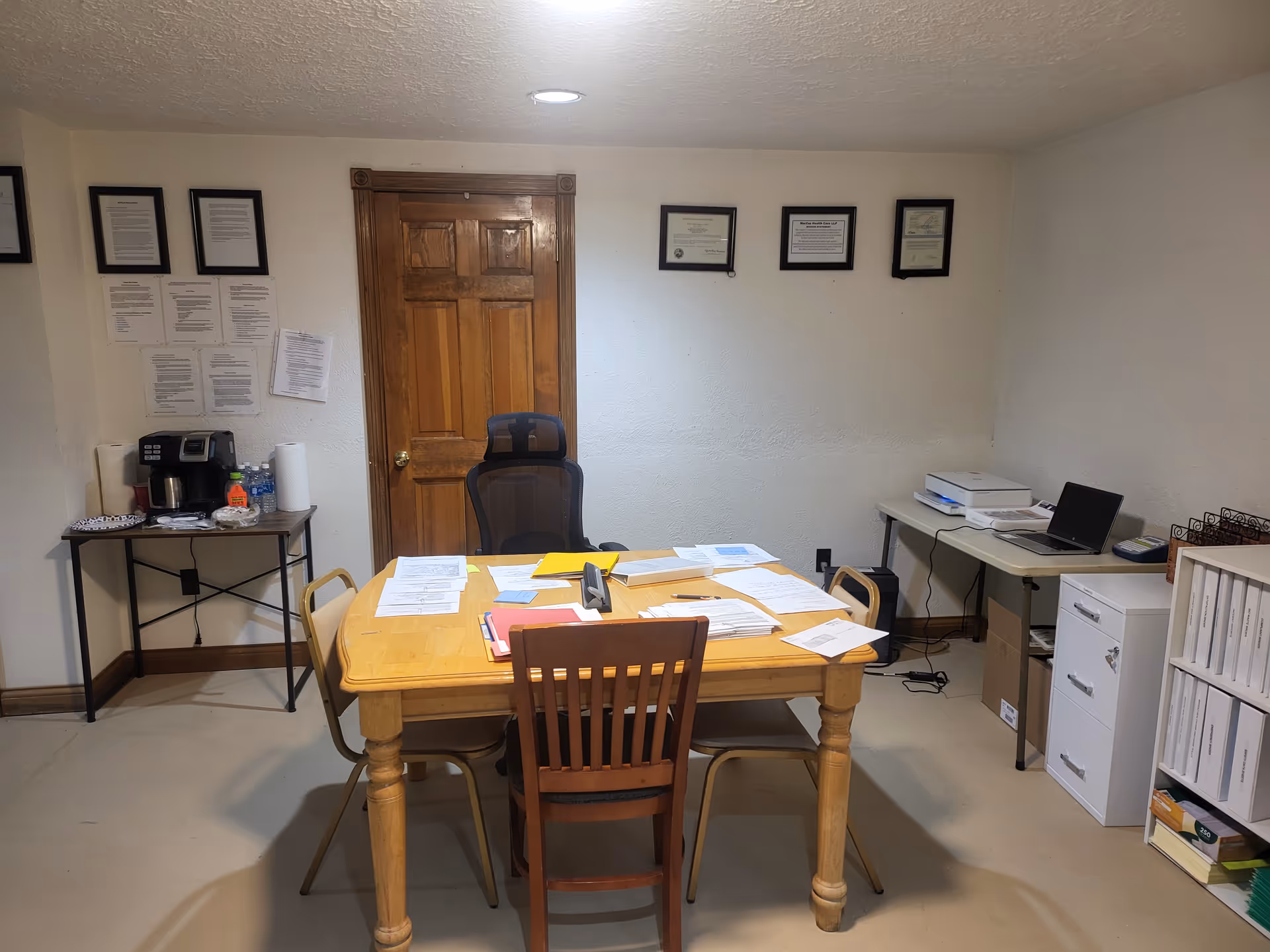 Administrative office in a care facility with table, chair, documents, and equipment.
