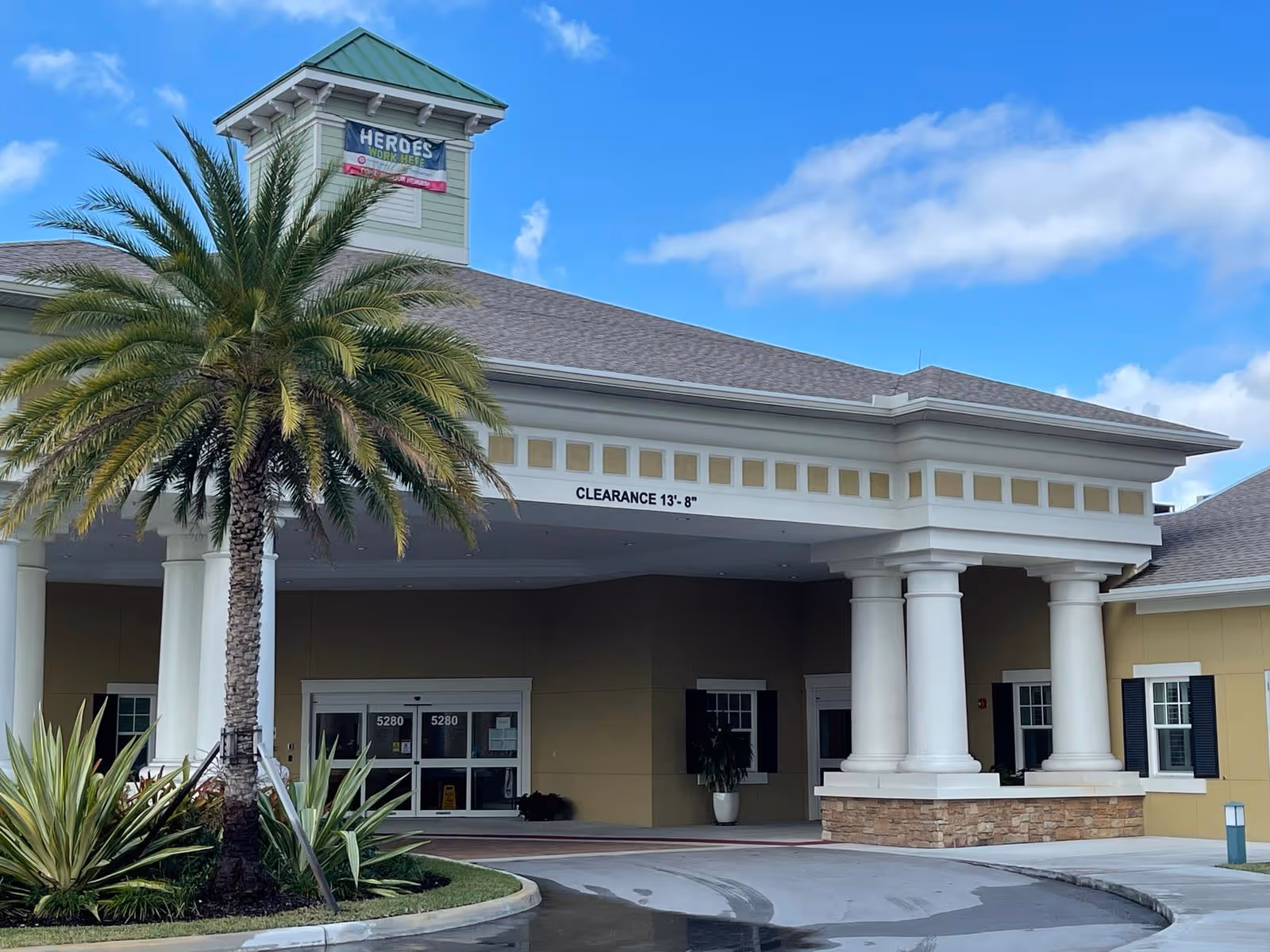 Kendall Lakes Health and Rehabilitation Center exterior entrance with columns, palm trees, and blue sky.