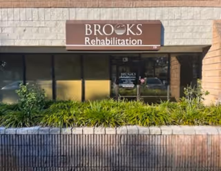 Exterior view of Brooks Rehabilitation Home Health Ocala storefront with sign and greenery.