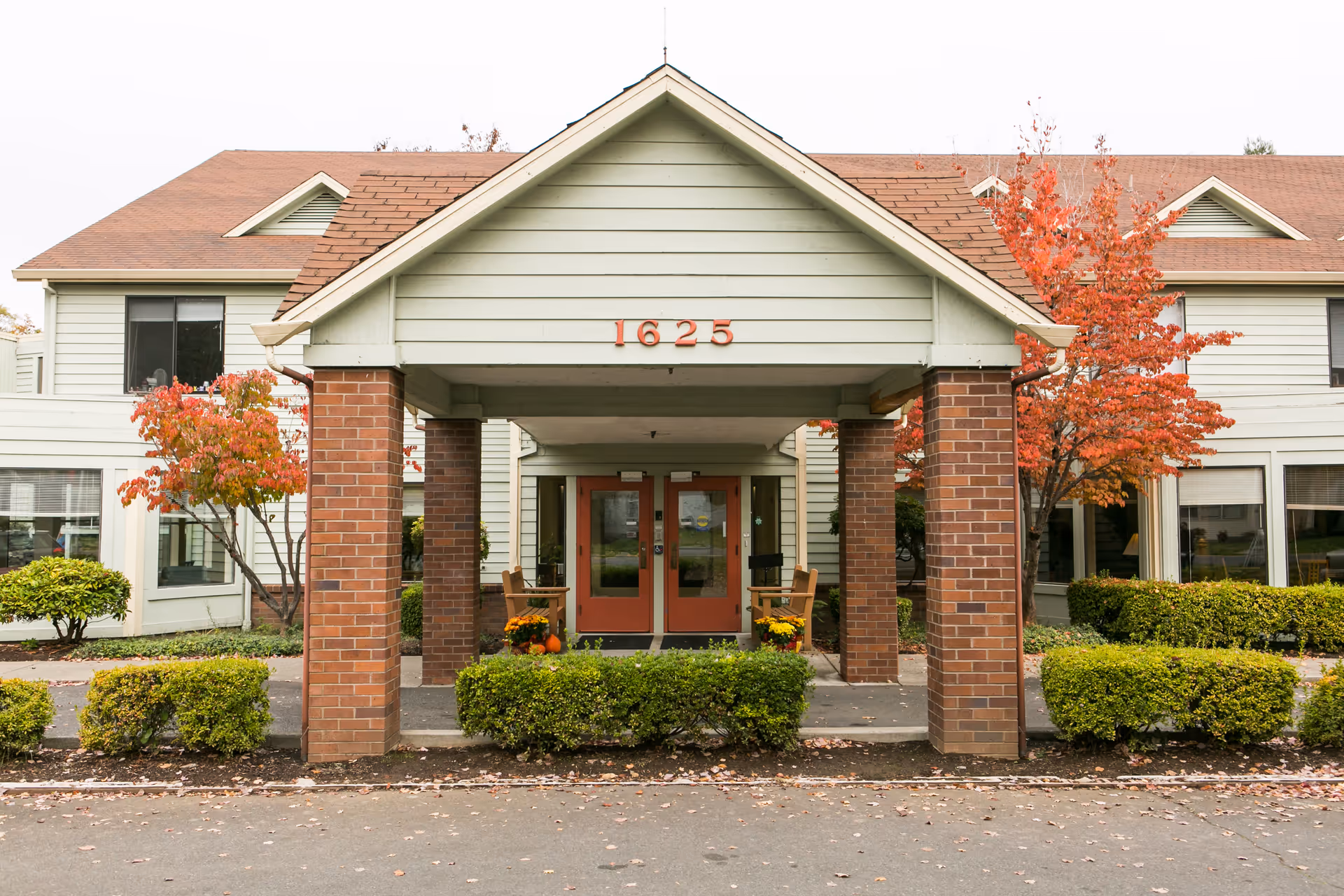 Front entrance of Willson House Residential Care with brick columns, red doors, and autumn trees