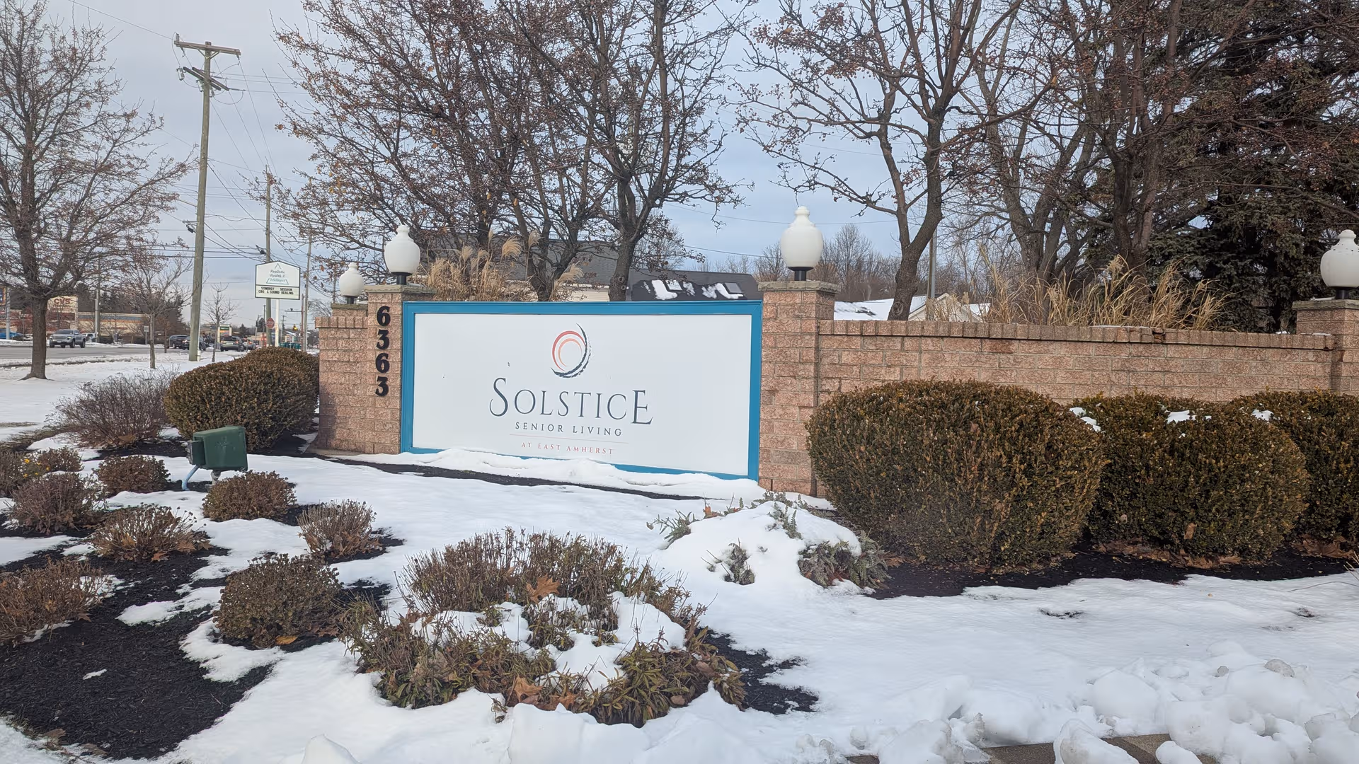 Sign for Solstice Senior Living at East Amherst in a snow-covered exterior landscape.
