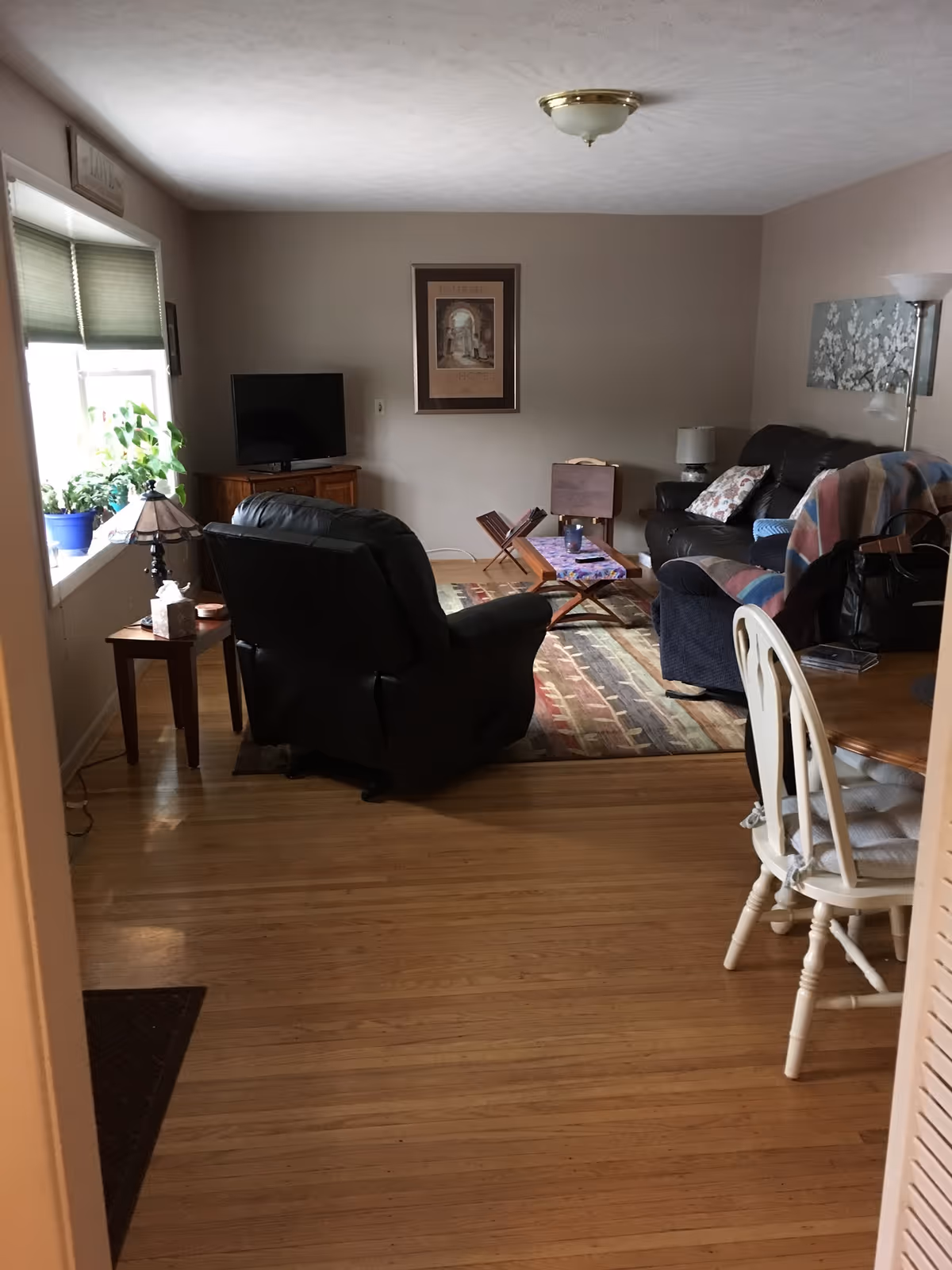 Cozy living room with recliner, sofa, TV, and coffee table in a homey setup.
