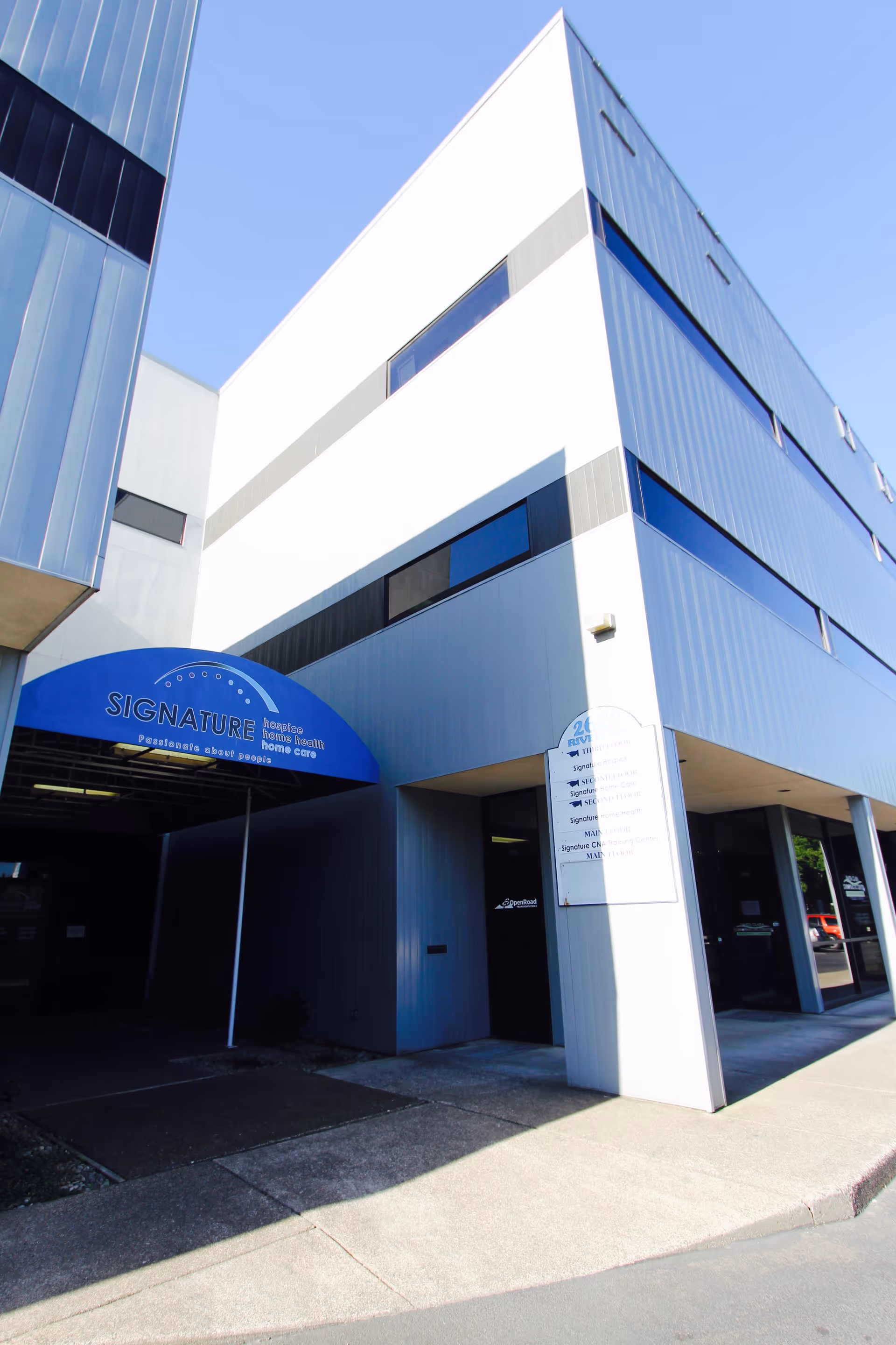 Modern angular building exterior with a blue entrance canopy labeled Signature Hospice.