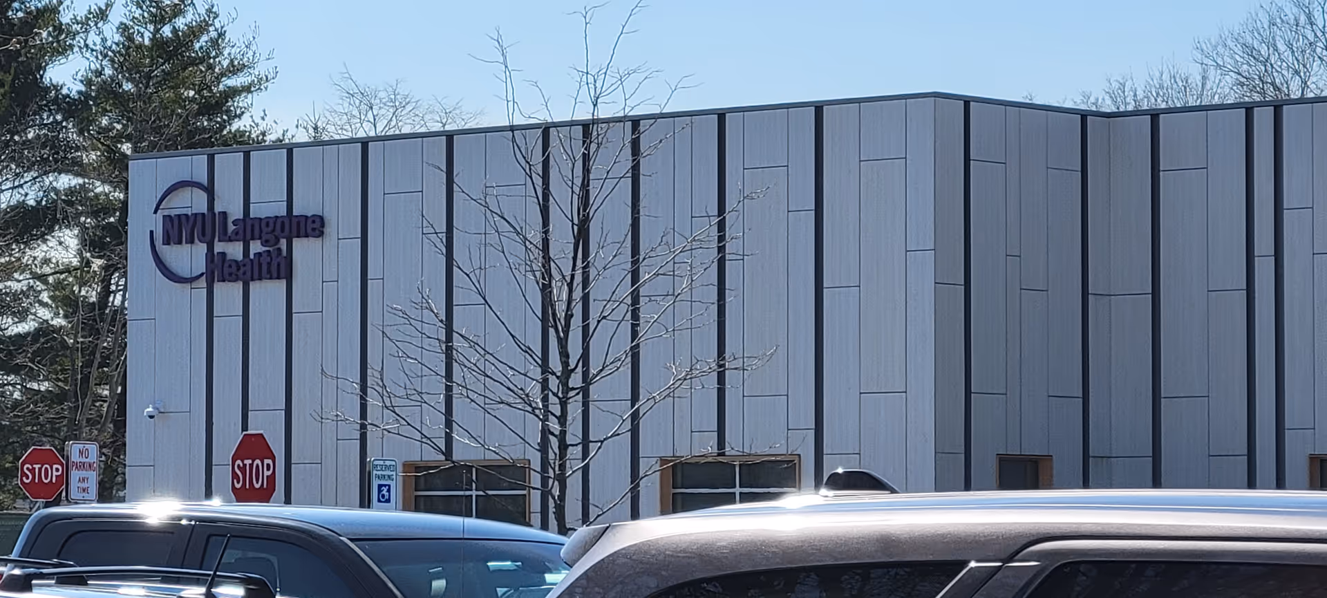 Modern gray building facade with NYU Langone Health sign and parked cars in front