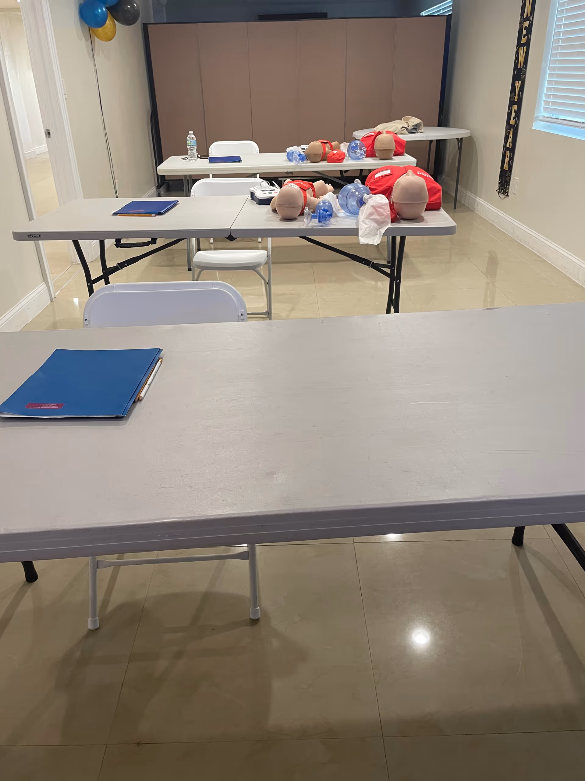 A training room with CPR mannequins and supplies arranged on folding tables.