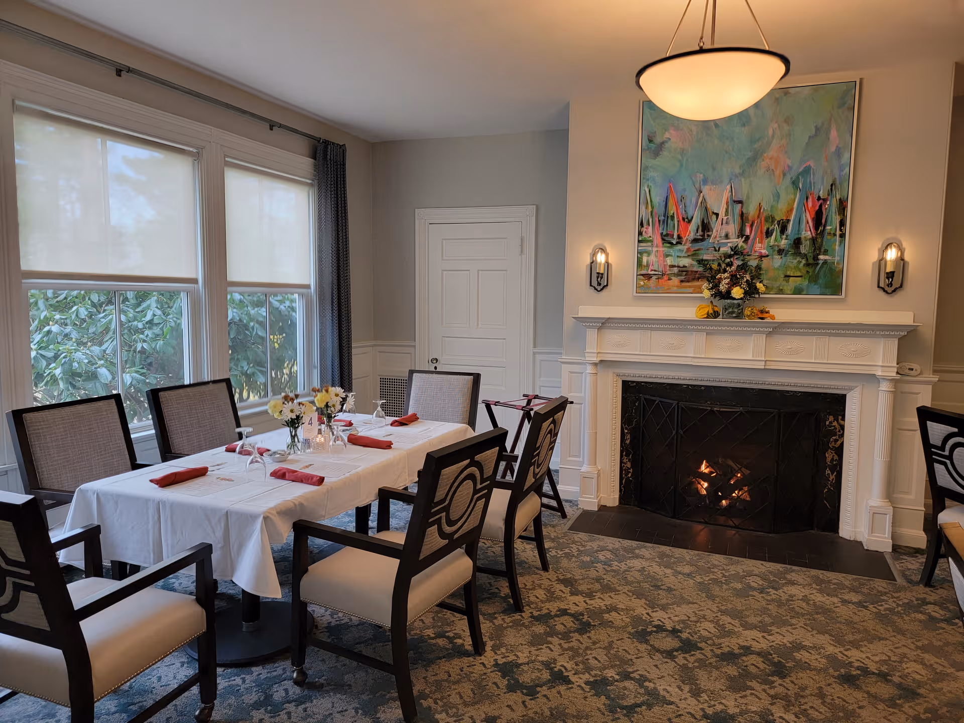 A formal dining room with a long table, chairs, fireplace, and floral centerpiece.