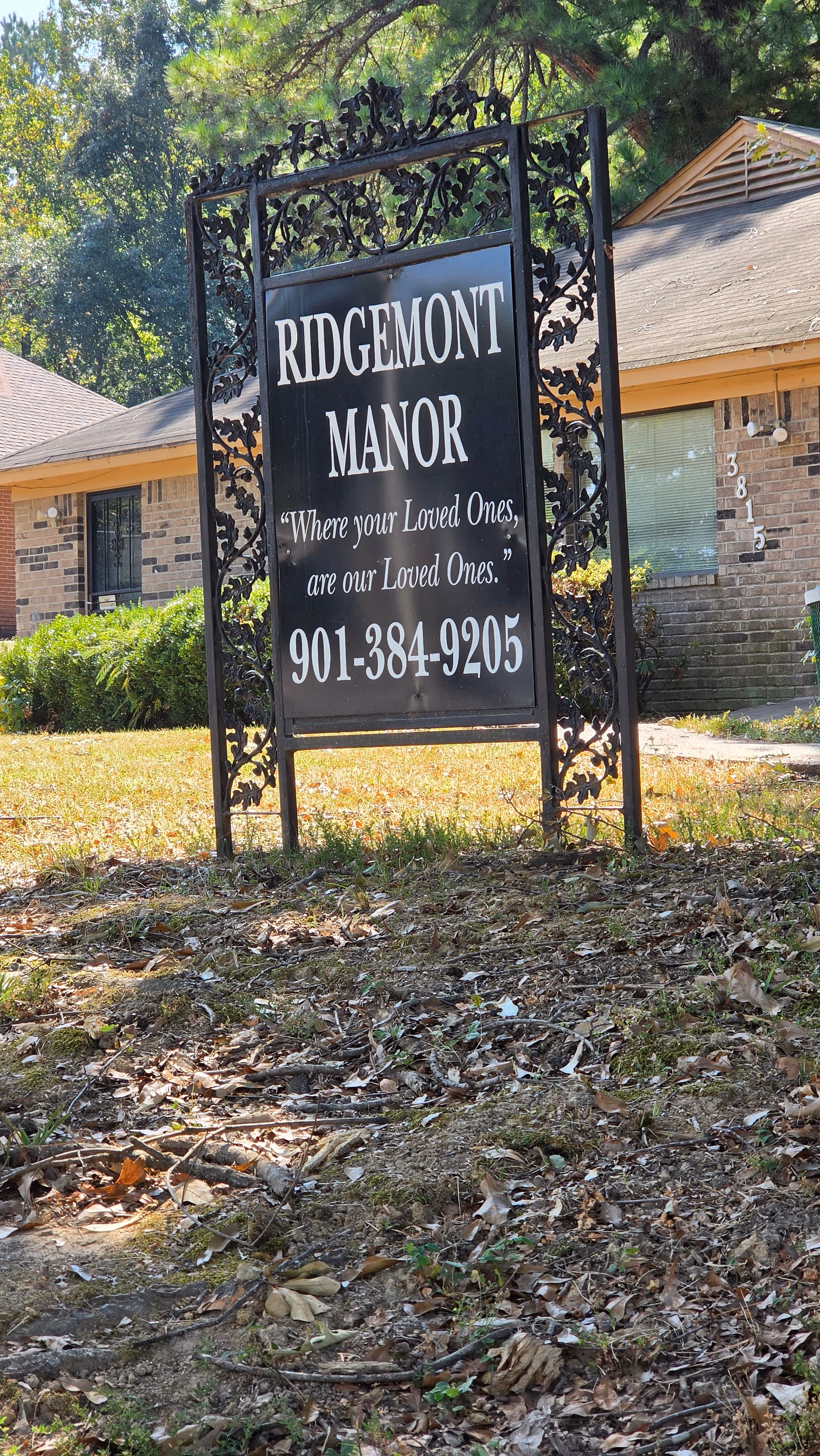 Ornate Ridgemont Manor sign on lawn with brick building behind.