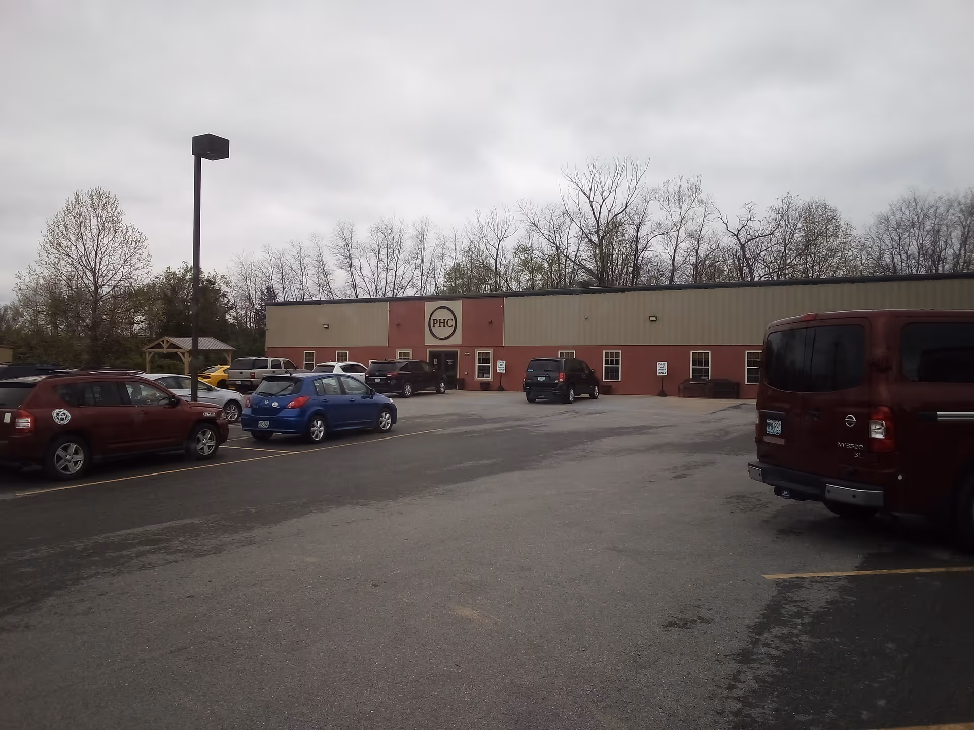 Parking lot in front of a single-story building with a PHC sign.