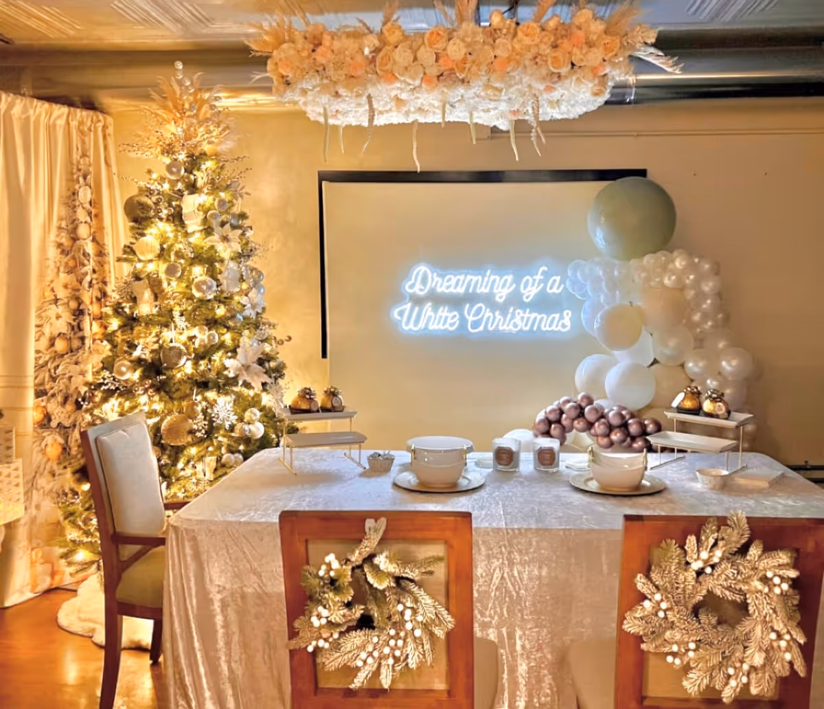 Festively decorated dining table with Christmas tree, ornaments, and neon backdrop.