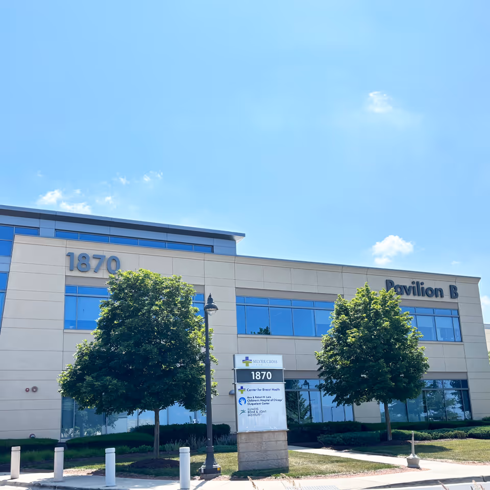 Modern medical building front with address 1870, Pavilion B sign, glass windows, and trees.