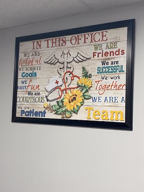 Framed office wall sign with inspirational teamwork phrases and a sunflower illustration.