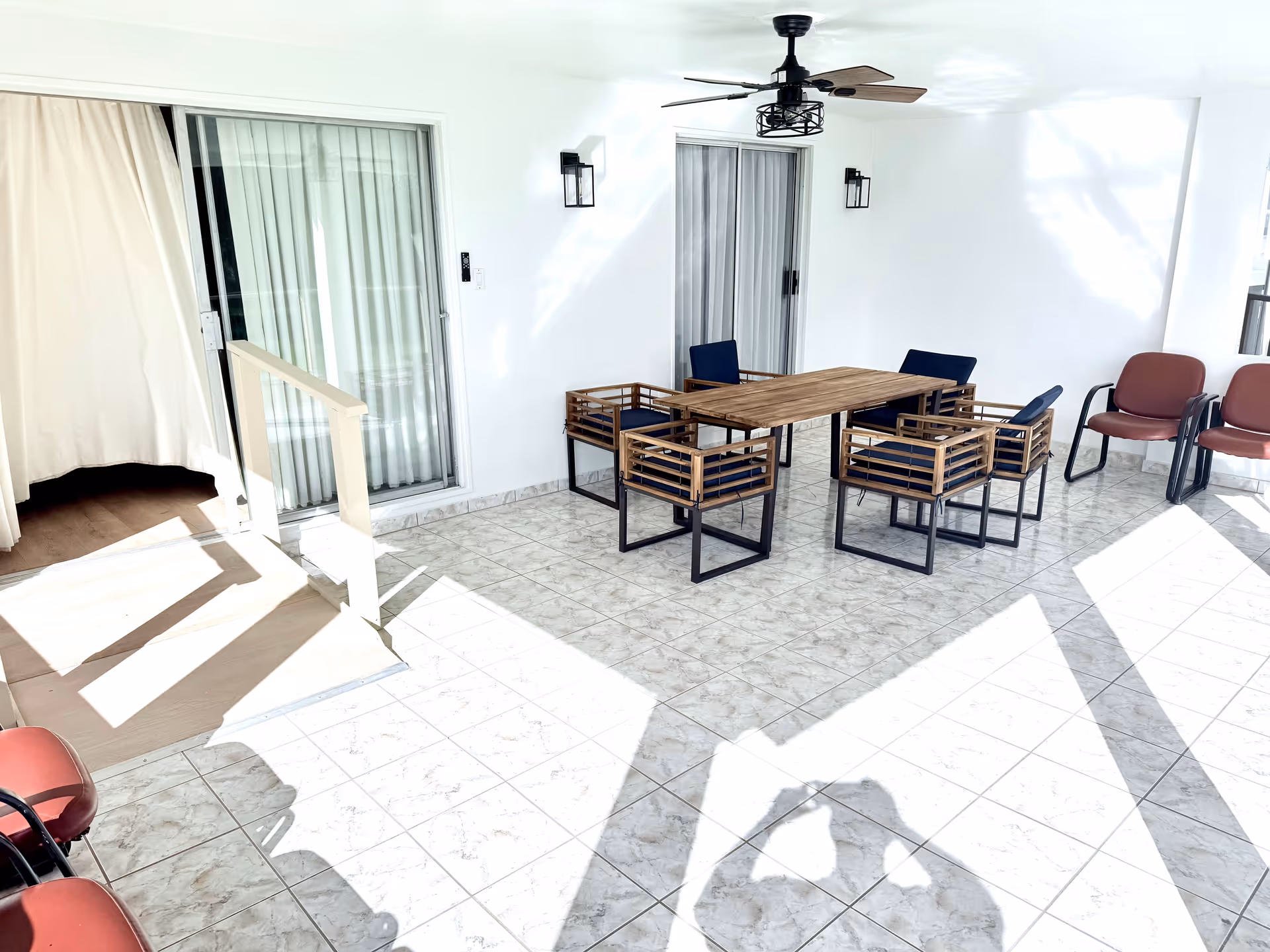 Outdoor patio area with a wooden table, chairs, and a ceiling fan.
