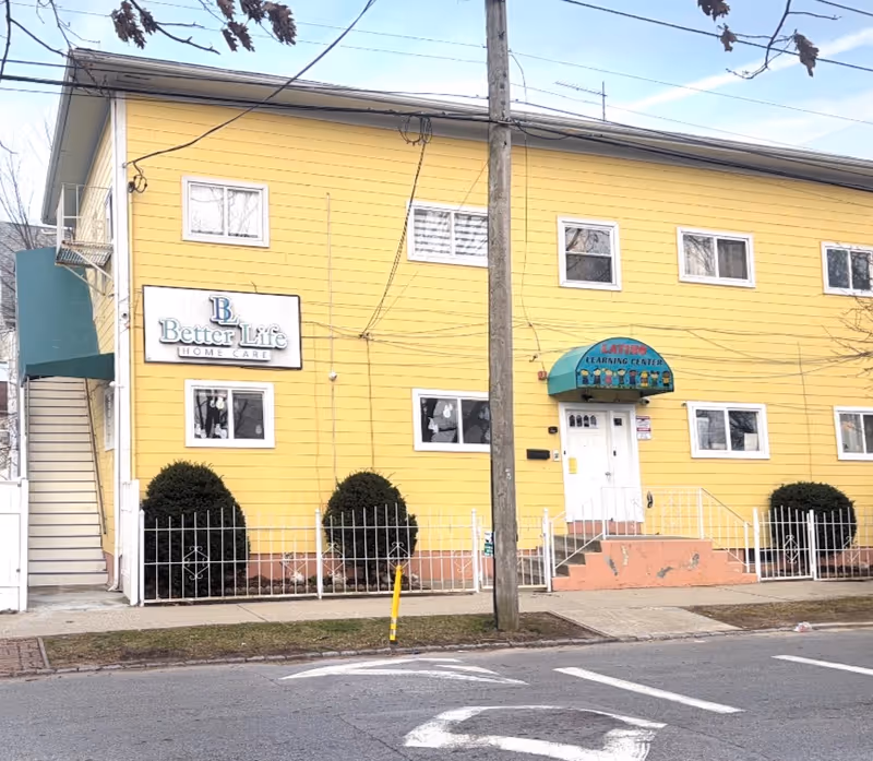 Yellow two-story building with Better Life Home Care sign and white fenced entrance.