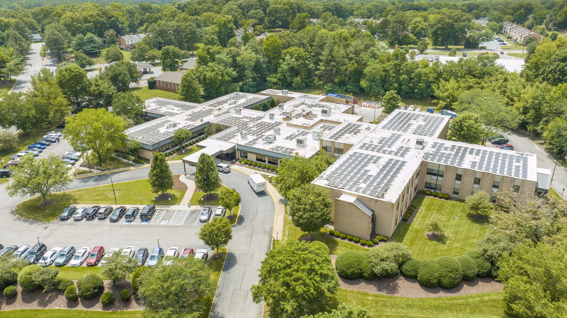 Aerial view of Lexington Court senior living campus with parking, trees, and solar-panel roofs.