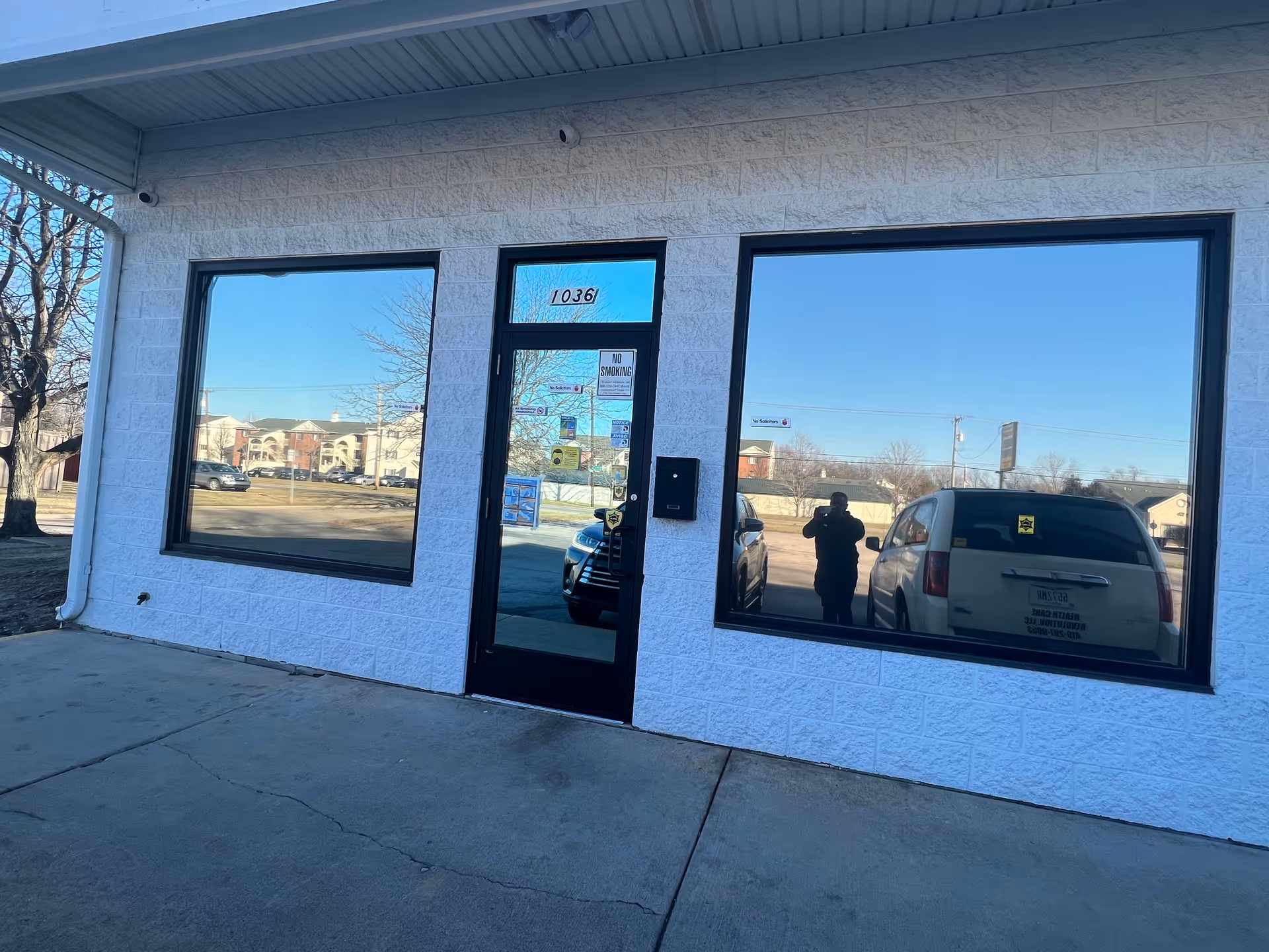 White brick senior care building front with black-framed windows and a central entry door