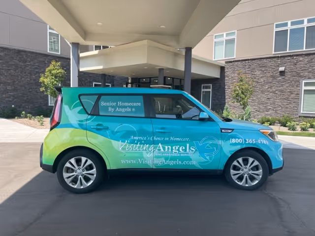 Colorful Visiting Angels van parked outside a modern senior home care facility entrance.