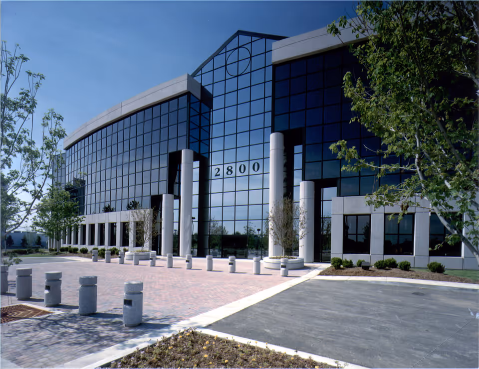 Modern glass-front building with tall white columns and a paved entryway.