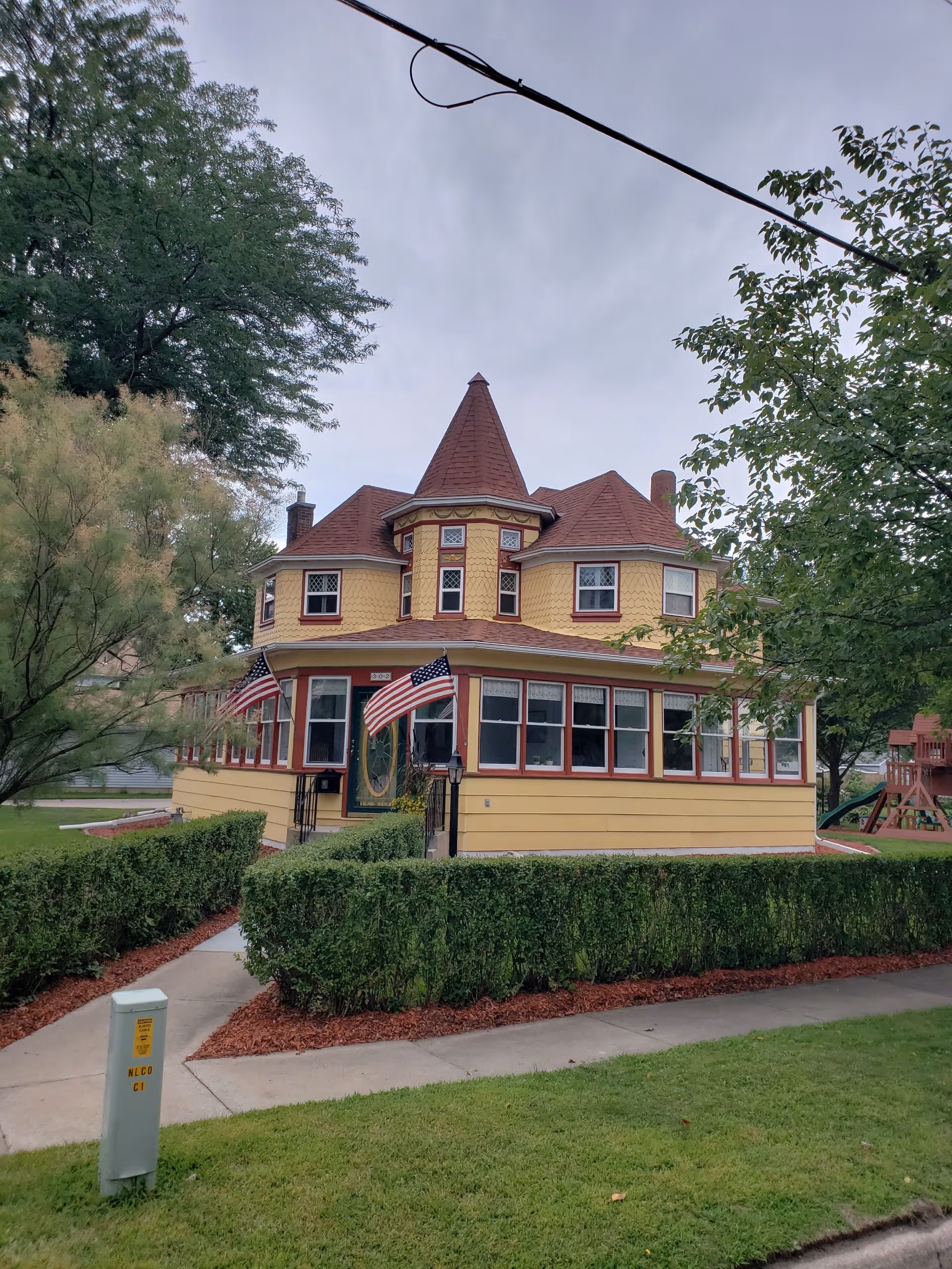 Castle-style yellow care facility with red turret roof, front walkway, and American flags