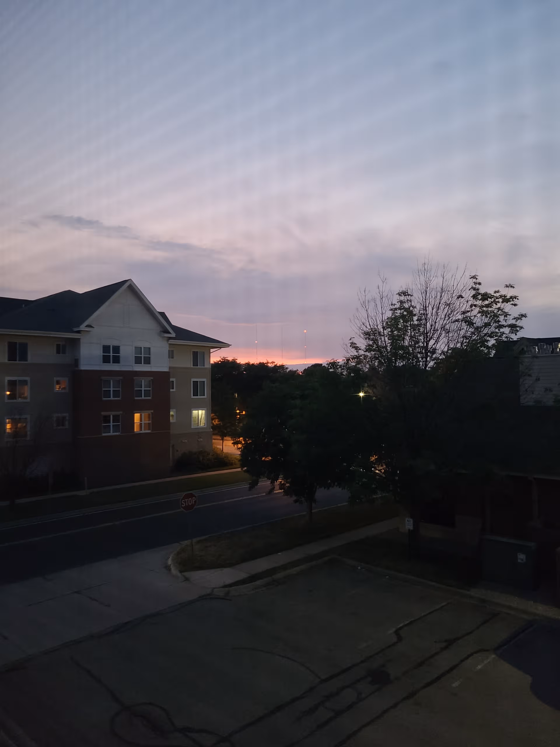 Exterior view of Glendale Place Apartments at dusk, showing a multi-story building, street, and trees.