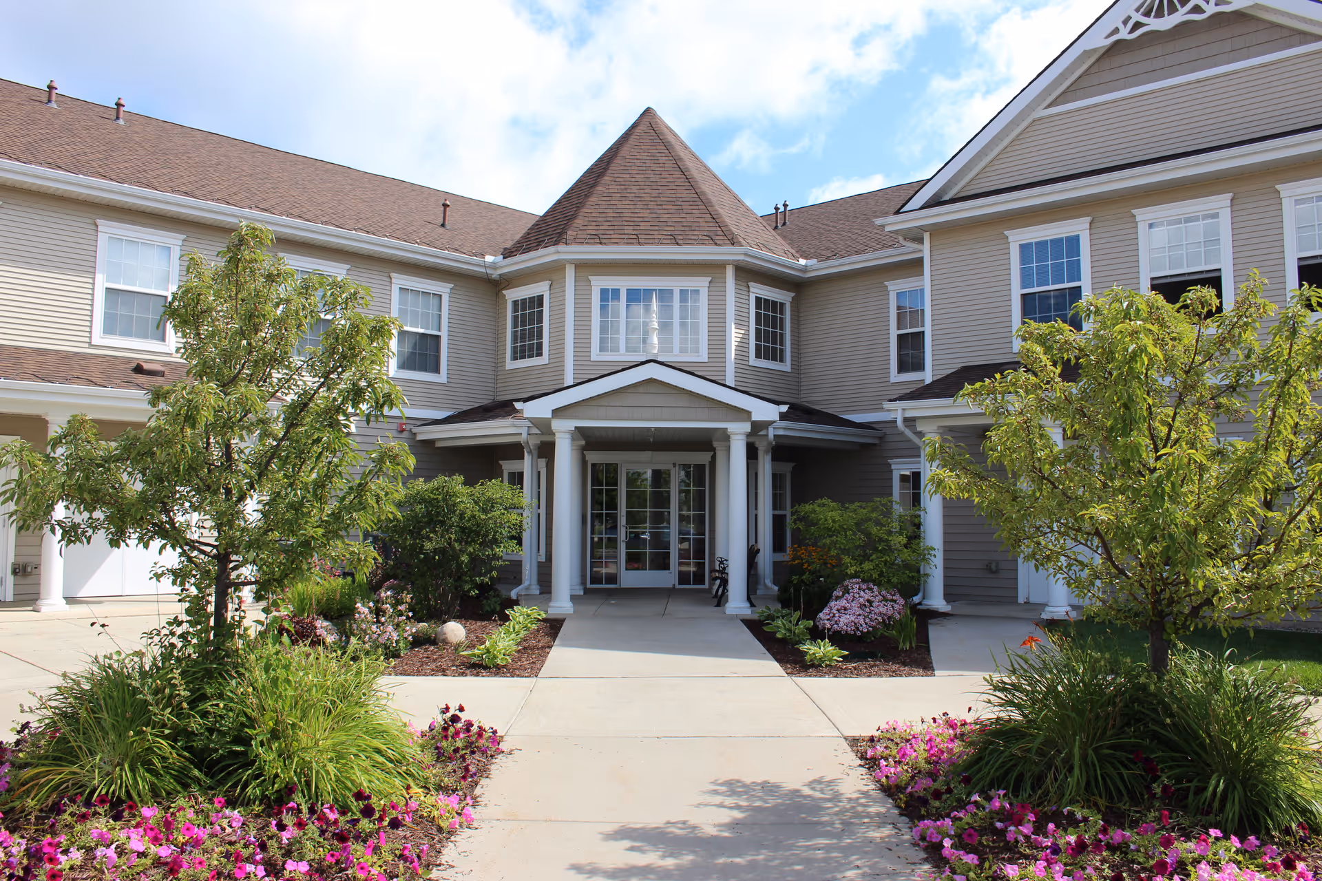 Front view of a senior living facility with covered entry and landscaped walkway.