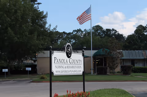 Exterior view of Panola County Nursing and Rehabilitation facility with a flag at the entrance.