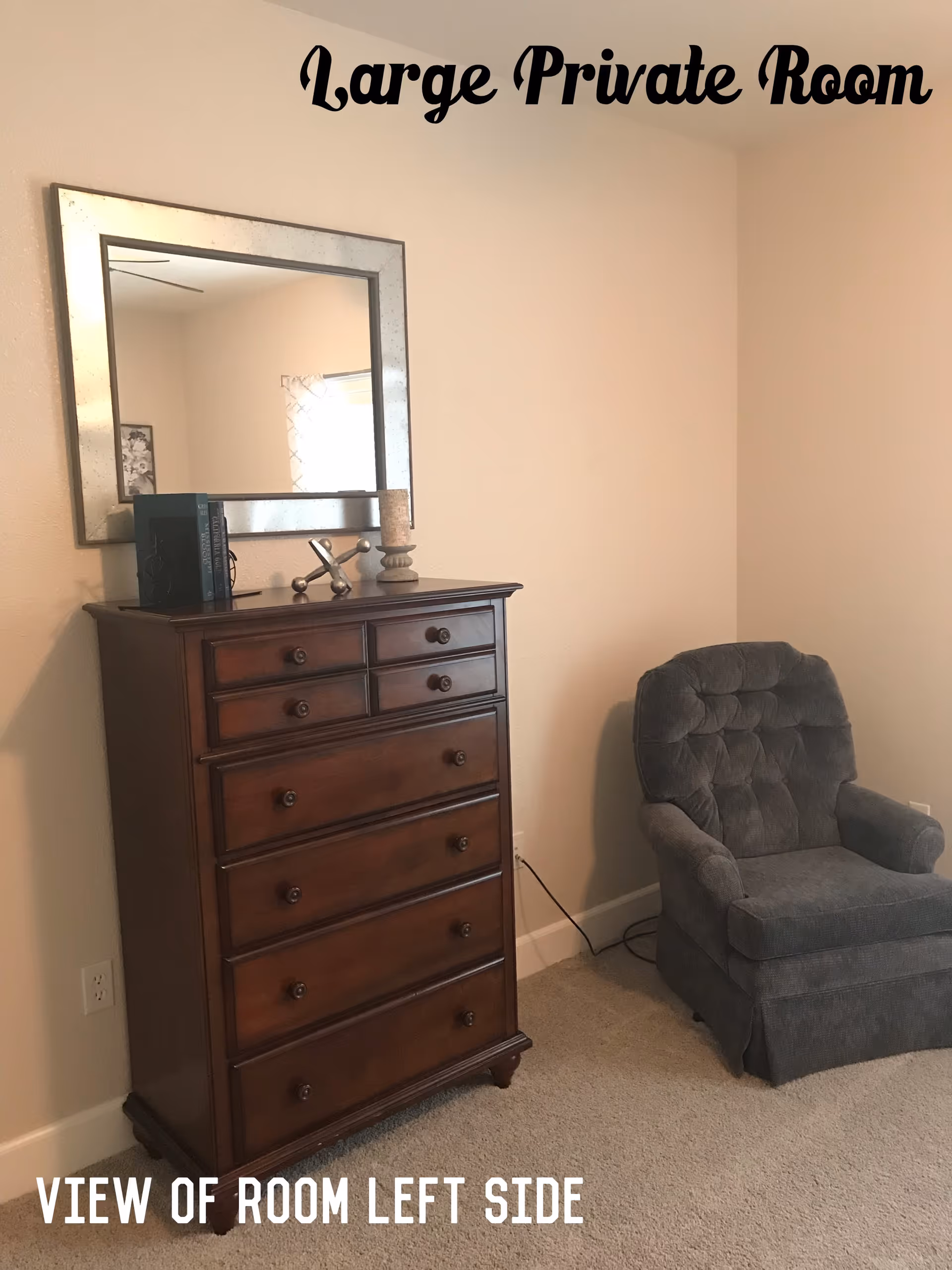 A private room with a wooden dresser, mirror, and gray armchair.