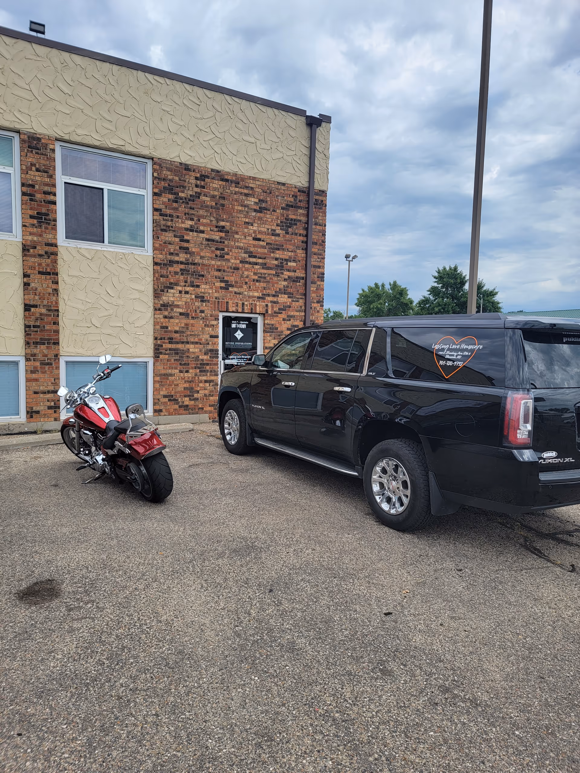 Exterior view of Lasting Love Homecare building with a black van and red motorcycle in front