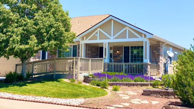 Exterior view of Gardens Care Senior Living Homestead with porch and landscaping.