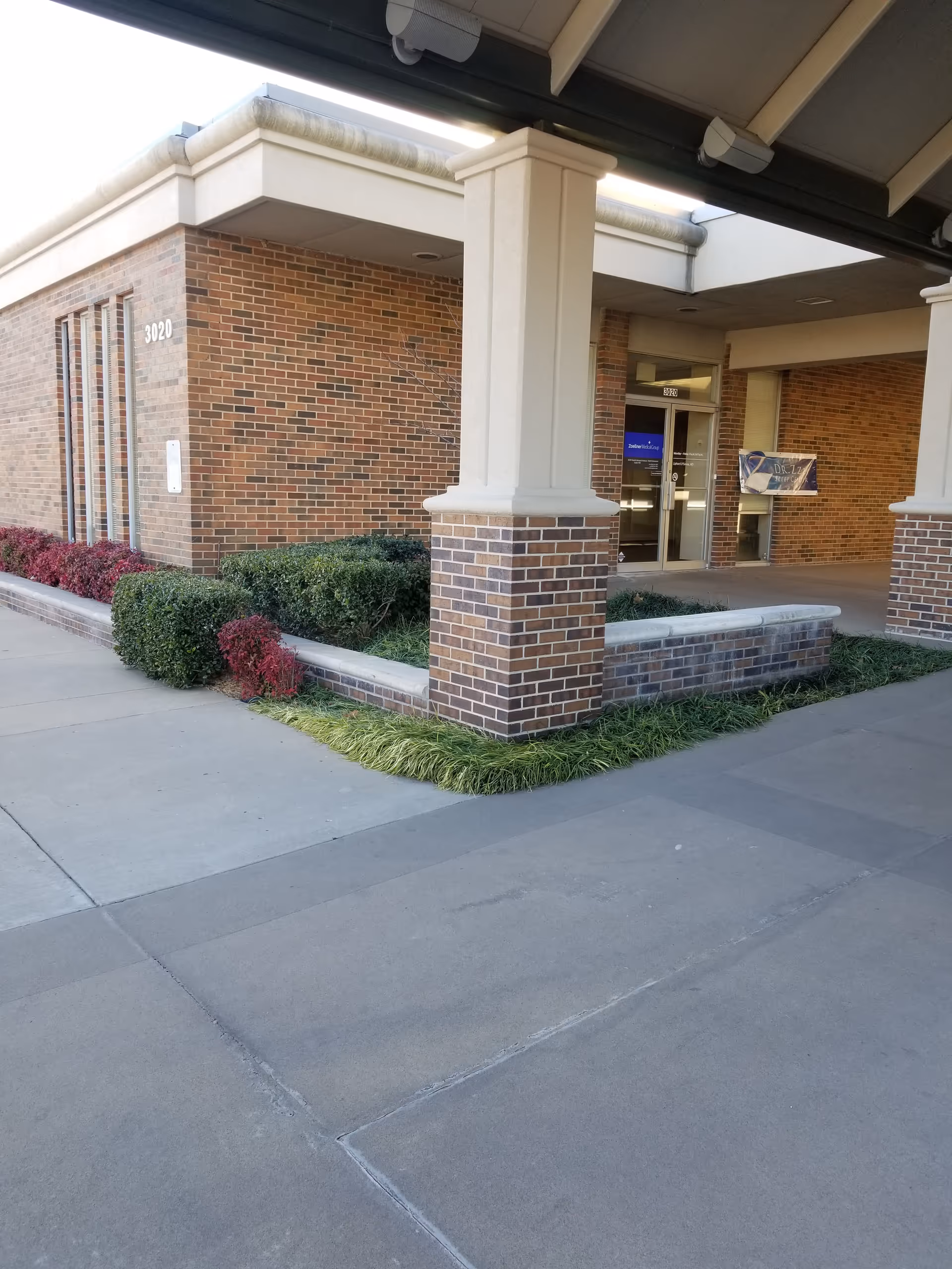 Exterior brick building of Oklahoma Advantage Storehouse with columns, glass doors, and manicured landscaping.