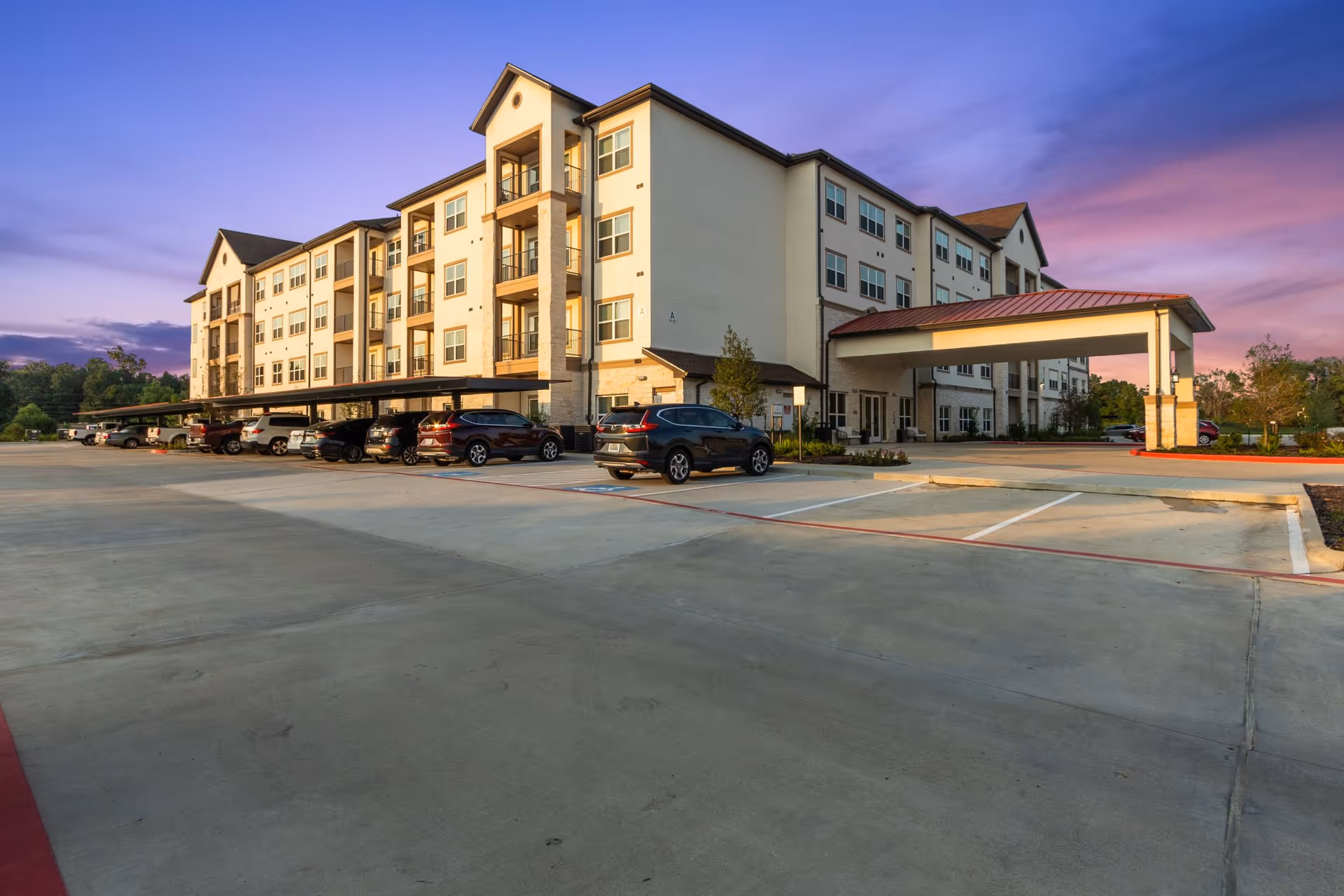 Exterior view of a multi-story senior living facility with a covered entrance and parking.