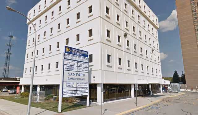 Tall white multi-story building with Sanford signs and street-level storefronts.