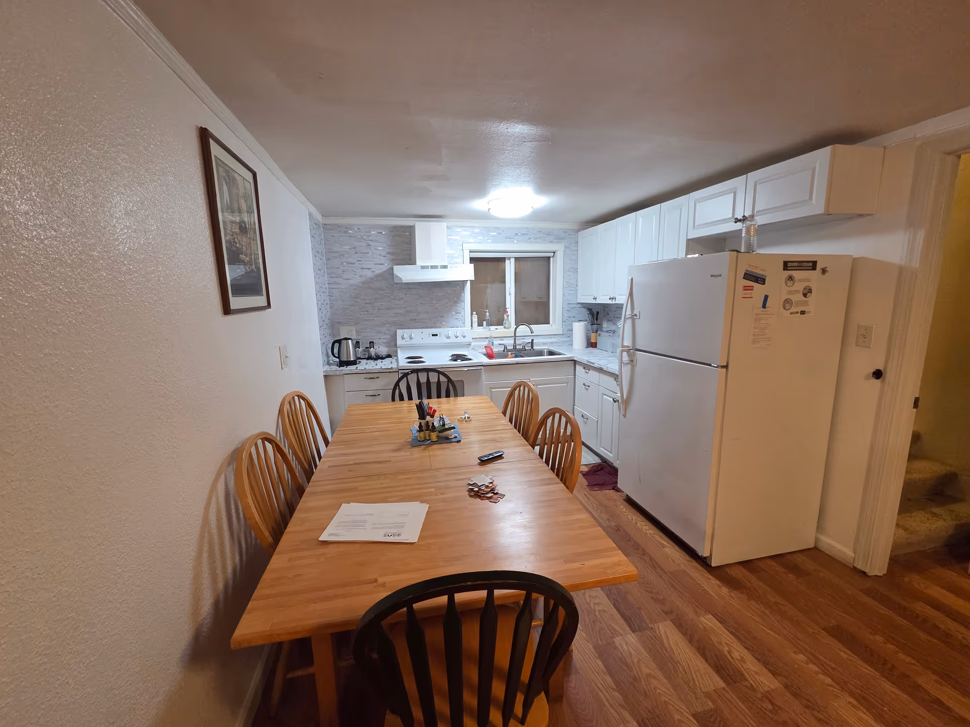 Wooden dining table with chairs in a compact white kitchen area.