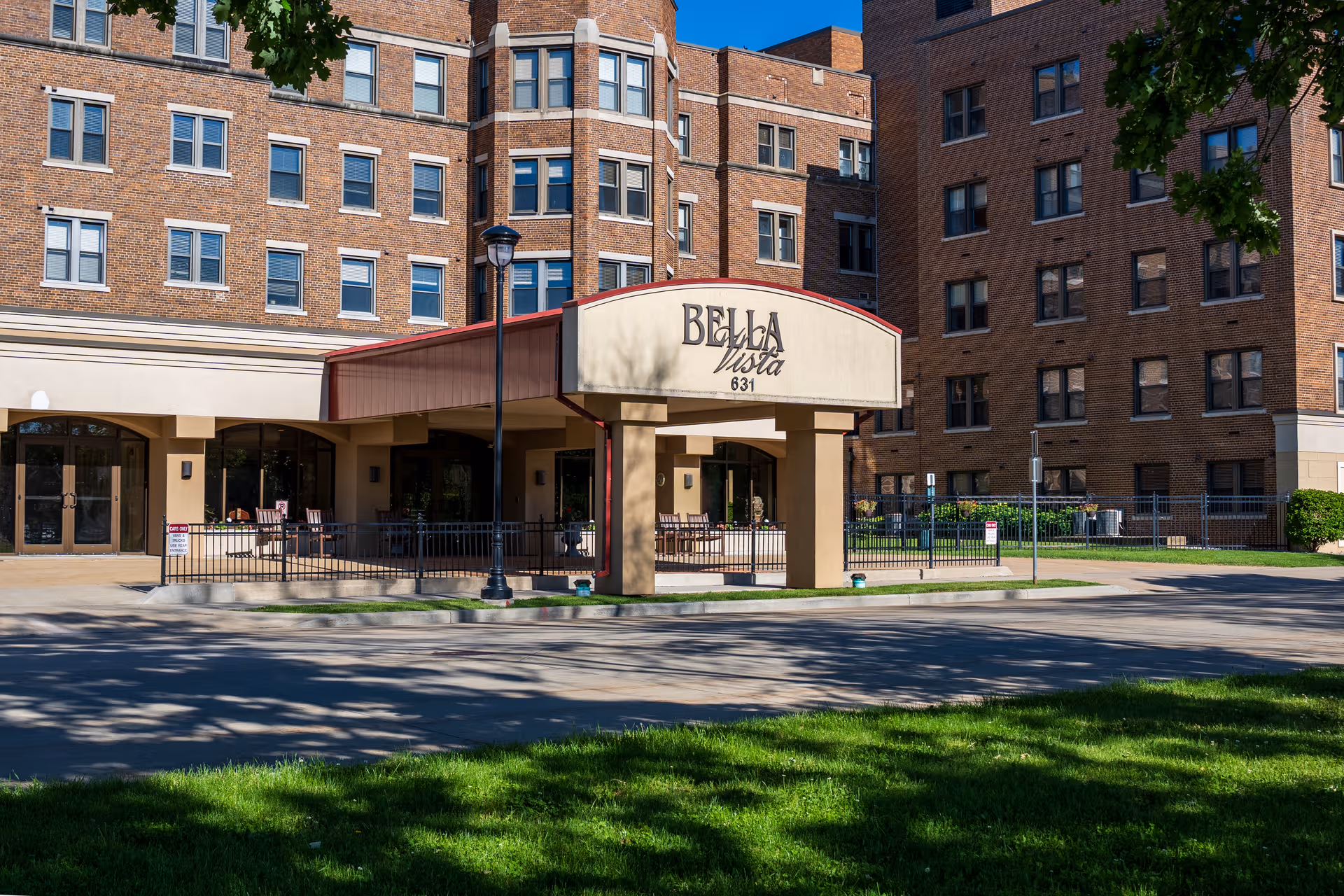 Exterior view of Bella Vista entrance with brick building and outdoor seating area.
