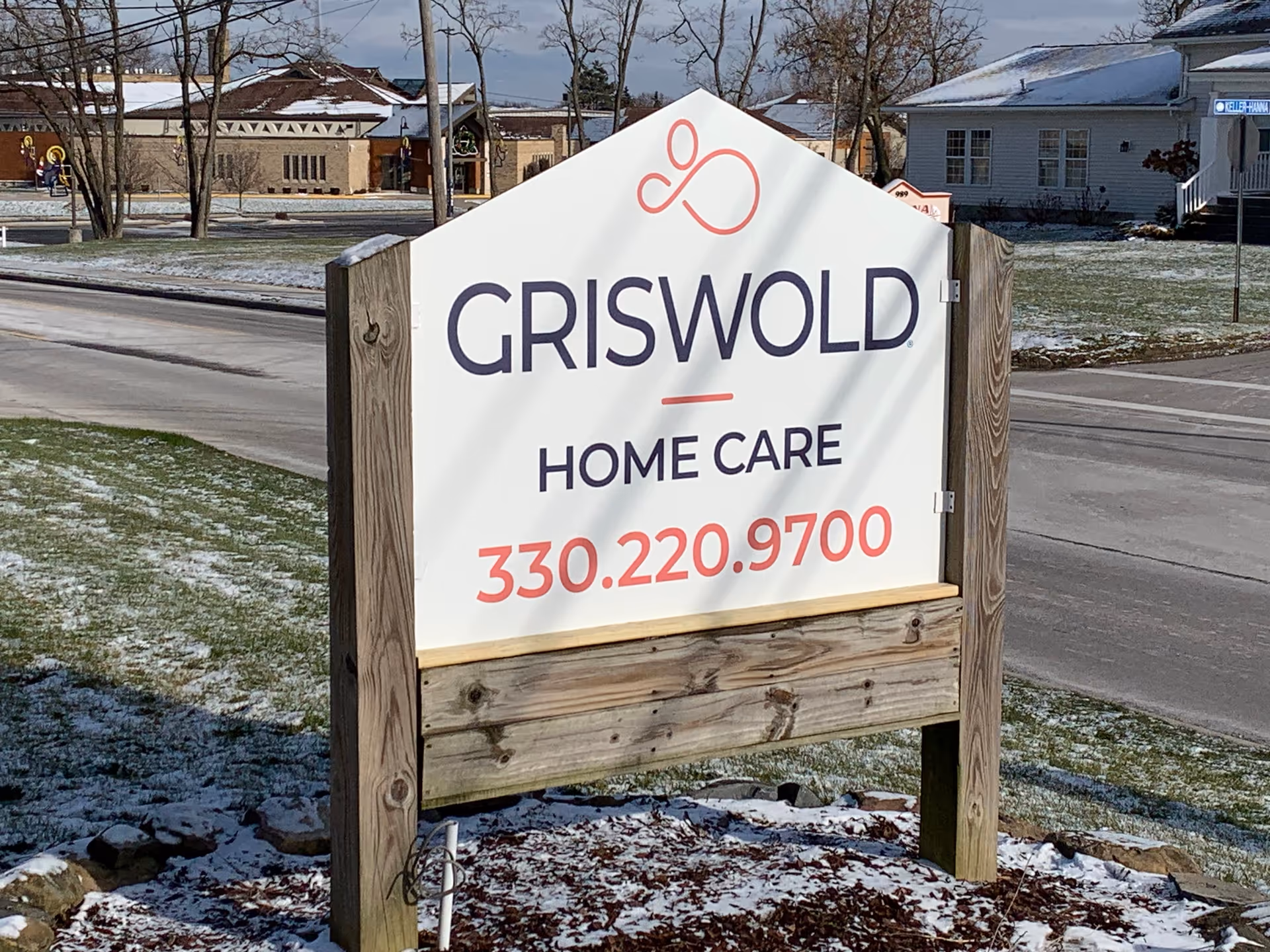 Griswold Home Care sign on a wooden frame in a snowy front yard.
