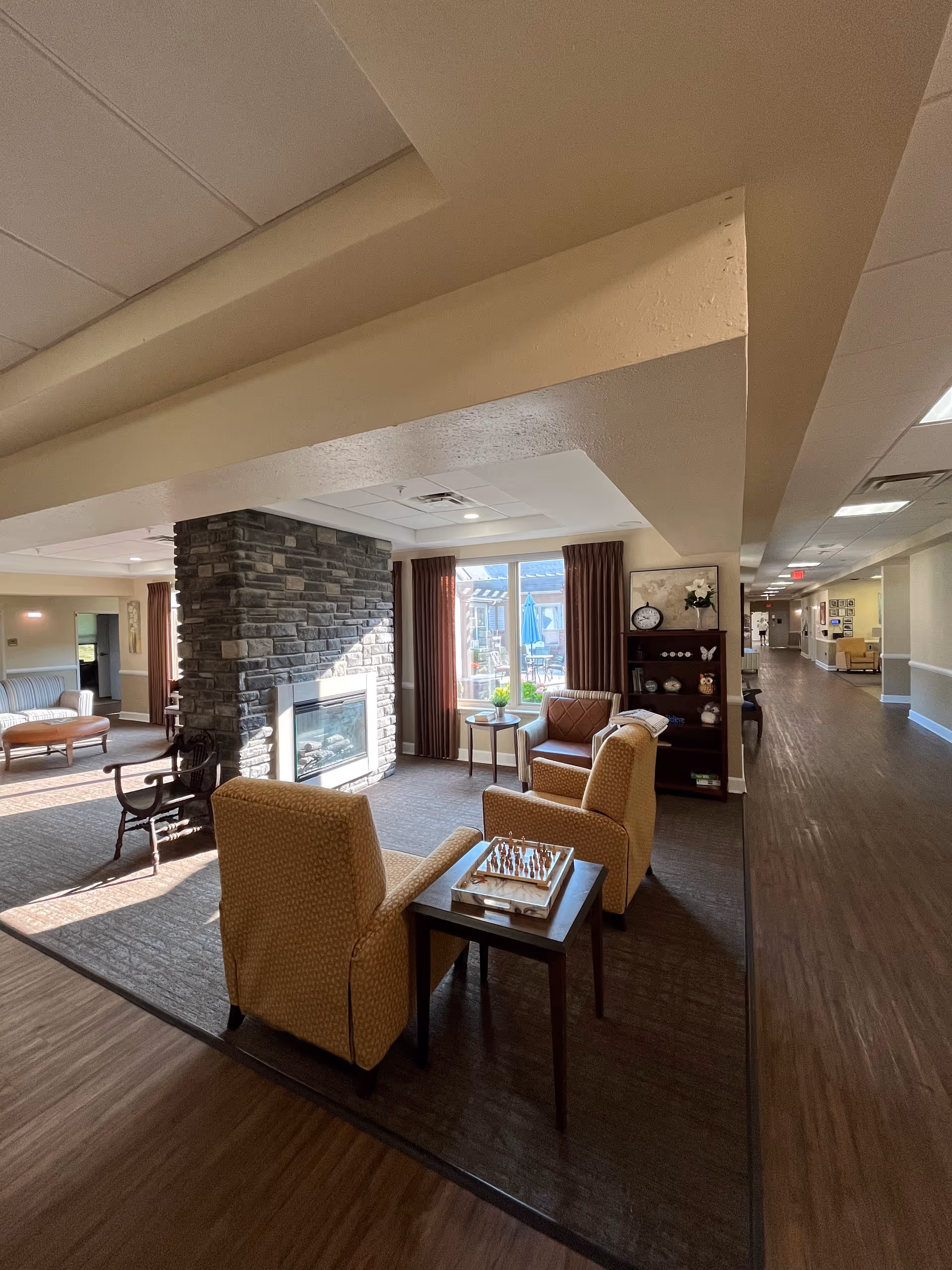 Spacious lounge area with comfortable chairs, a stone fireplace, and large windows.