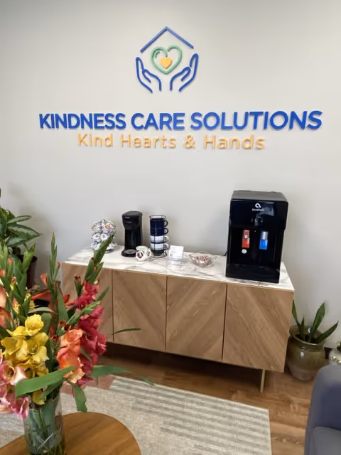 Interior lobby with Kindness Care Solutions signage and a coffee station on a wooden cabinet.